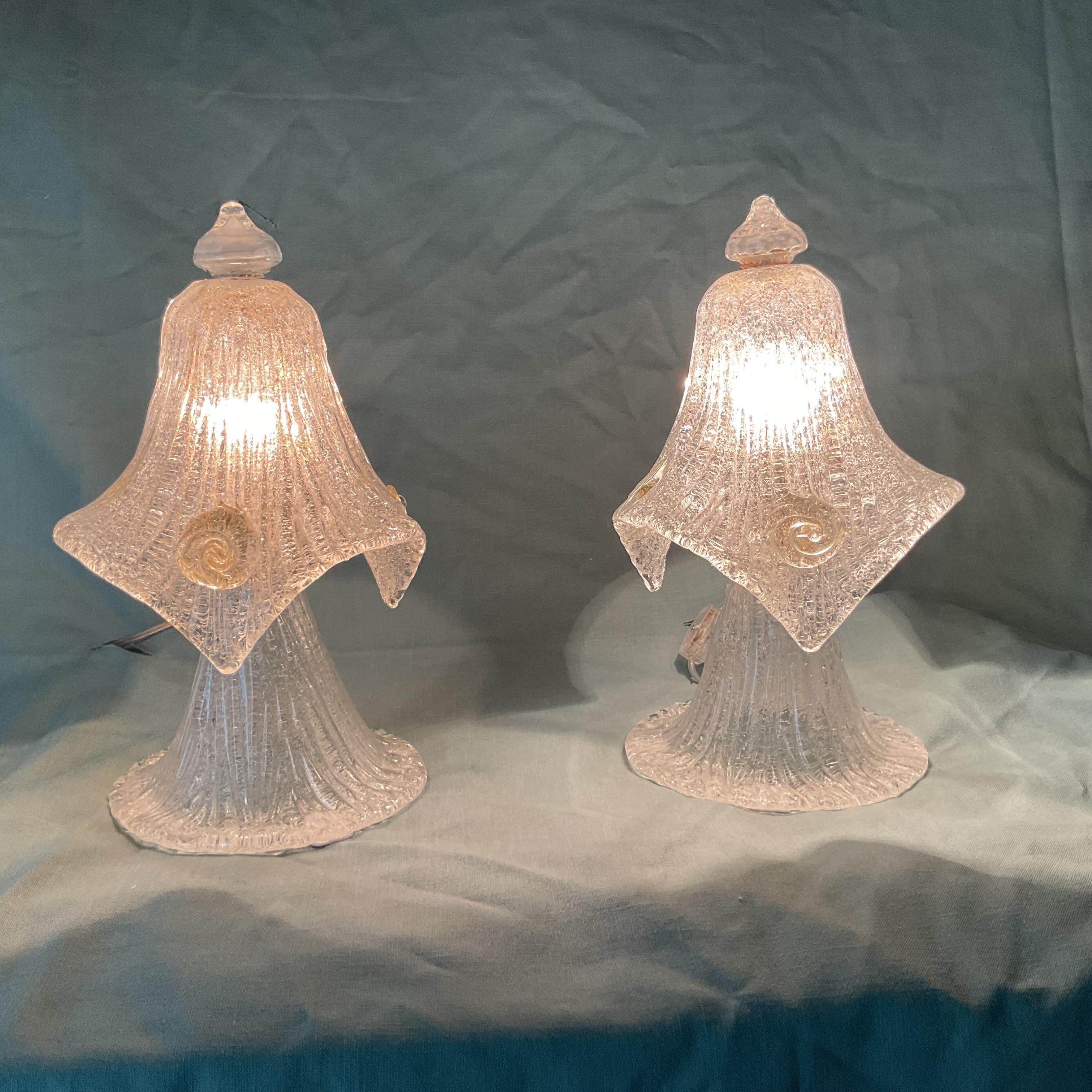 A stunning pair of vintage Venetian glass lamps. Each lamp is shaped like a delicate flower, with a rippled, petal-like shade and fluted base crafted from clear glass infused with subtle gold flecks. The glass features a textured, ribbed surface