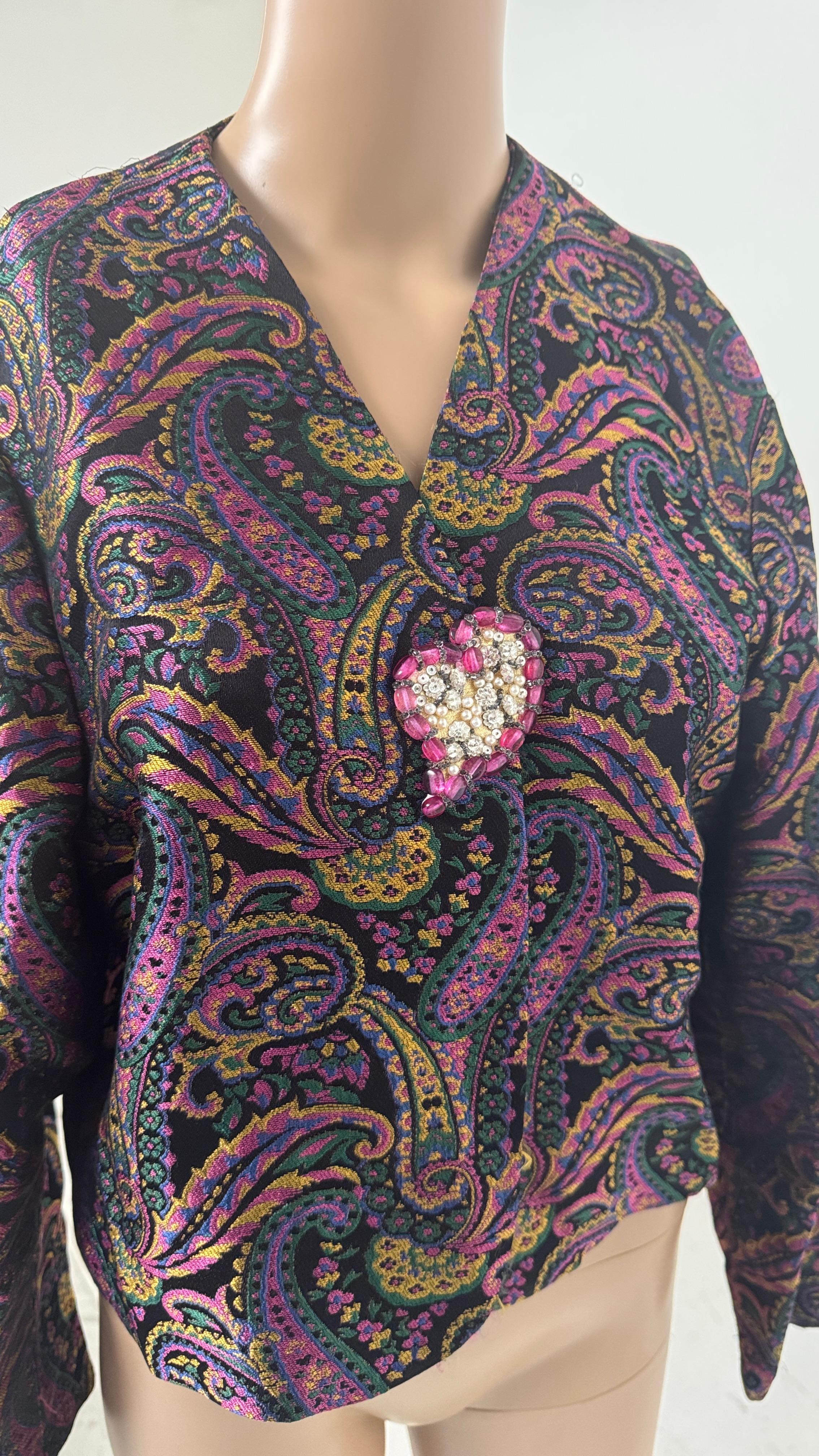 This striking vintage jacket features a rich paisley jacquard fabric woven in vibrant tones of fuchsia, emerald, mustard, violet and deep black. The intricate pattern creates a mesmerizing effect, giving depth and luxury to the piece. The silhouette