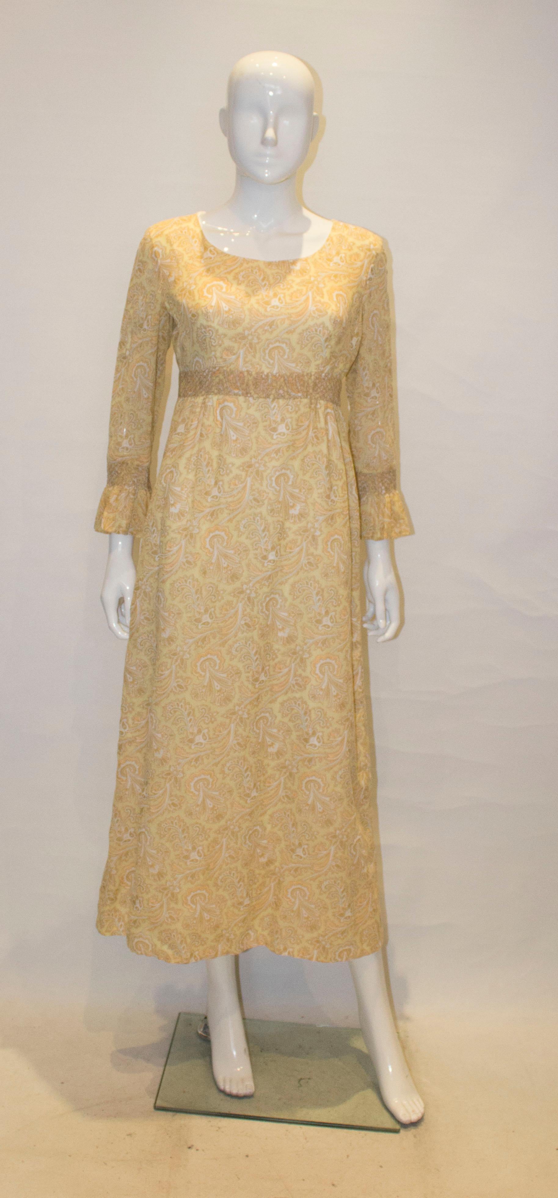 A pretty dress for Spring, in a pale yellow paisley print. The dress has elbow length selves with smocking detail, and there is smocking detail under the bust.  It is fully lined with a central back zip.