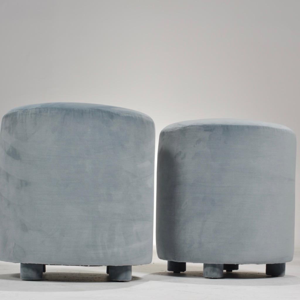 These cylindrical pale blue velvet ottoman stools feature four velvet-upholstered legs and a button on top. These are perfect for use as either an ottoman or additional comfortable seating. New upholstery. Sold individually.
  