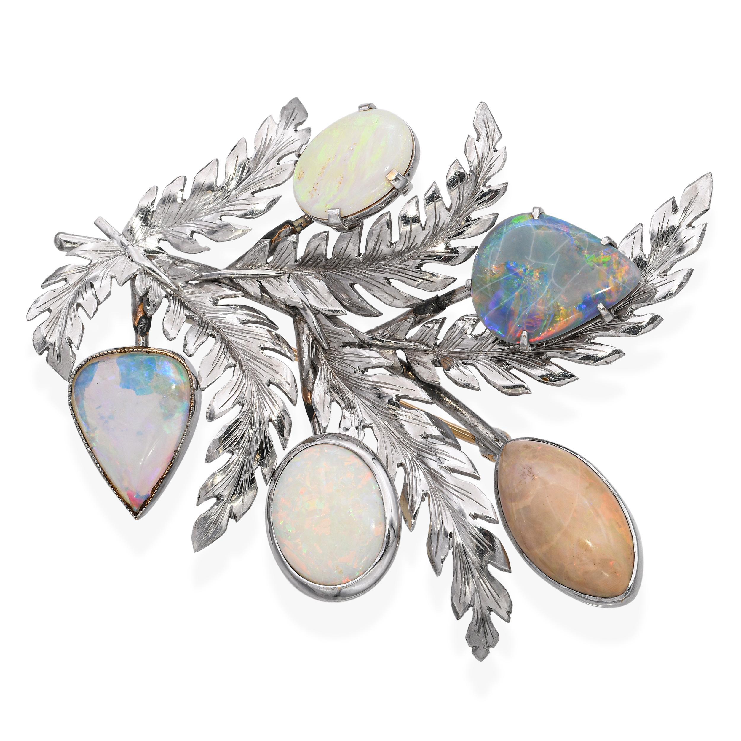 This unique vintage brooch is crafted in rare palladium, known for its bright silvery tone and durability, and features a graceful floral plant motif. Set within the organic design are shimmering opal cabochons, displaying vibrant flashes of color