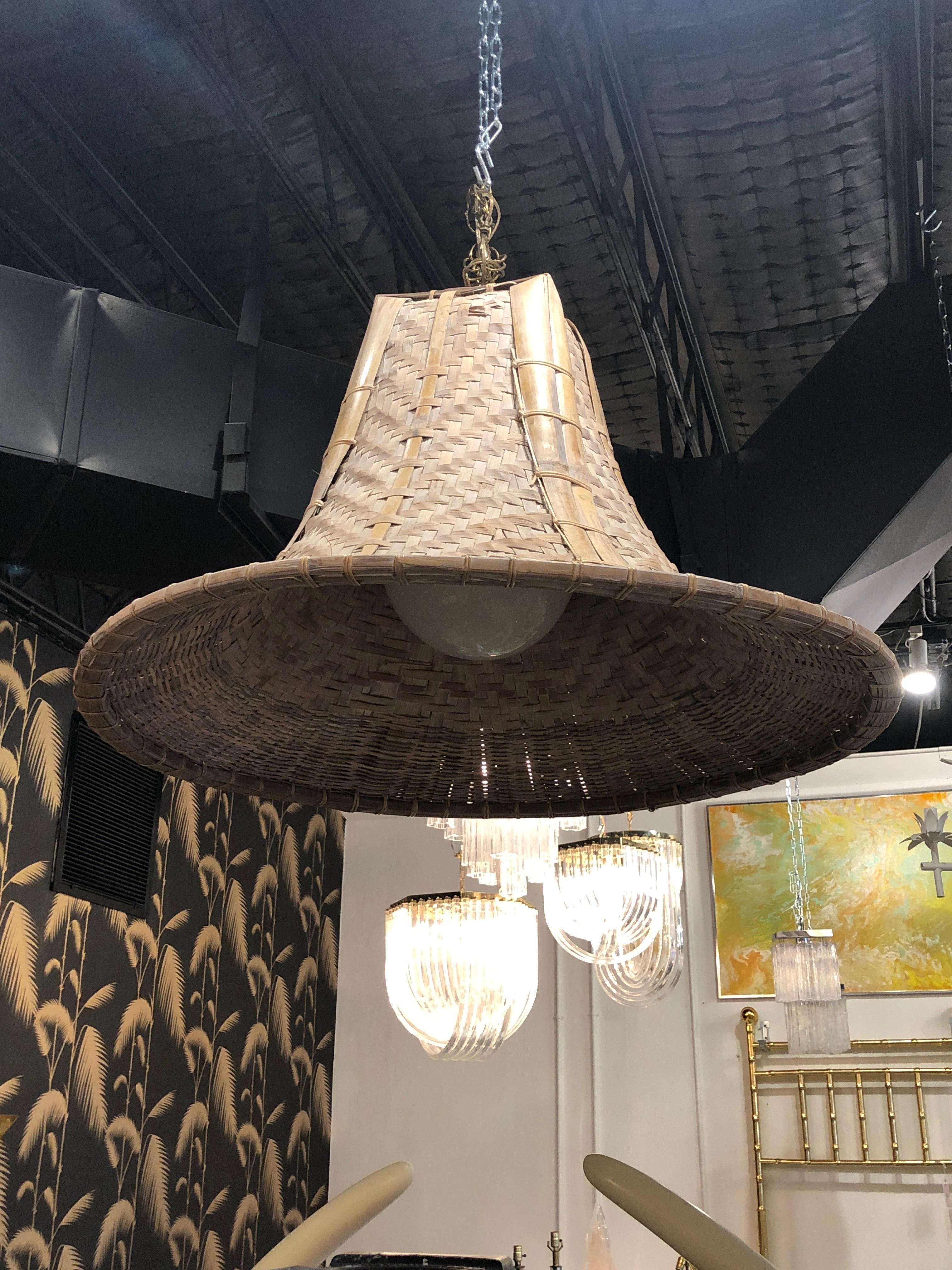 Uh-mazing! Vintage wicker and rattan chandelier. Measures: 36' diameter. Statement piece! Comes with chain, ceiling cap and globe light cover (inside). This could be lacquered or stained if you desired another color.