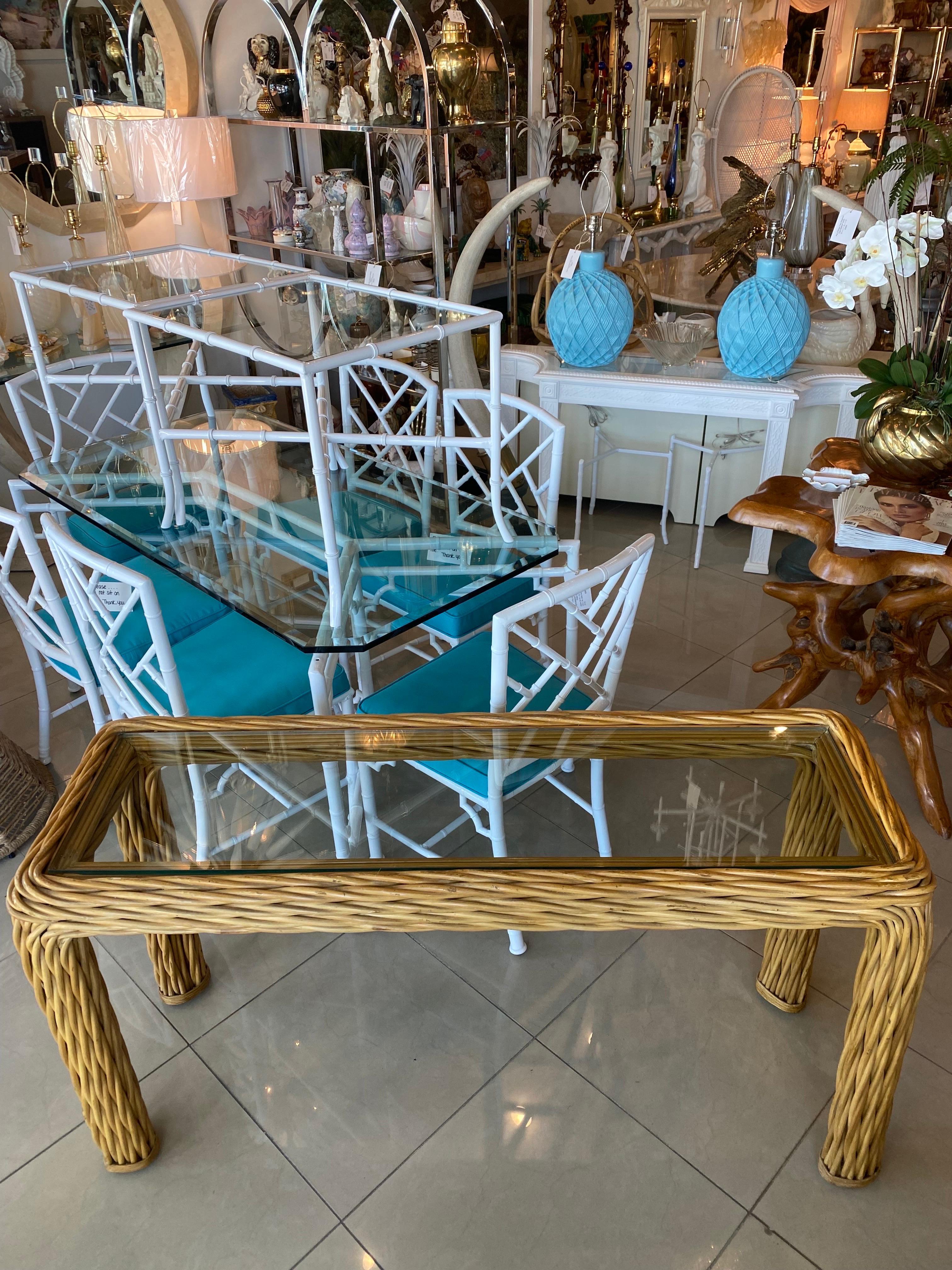 Lovely twisted rattan console table with new glass top Original vintage natural finish, may have some color variation. Dimensions: 28 H x 18 D x 58 L.