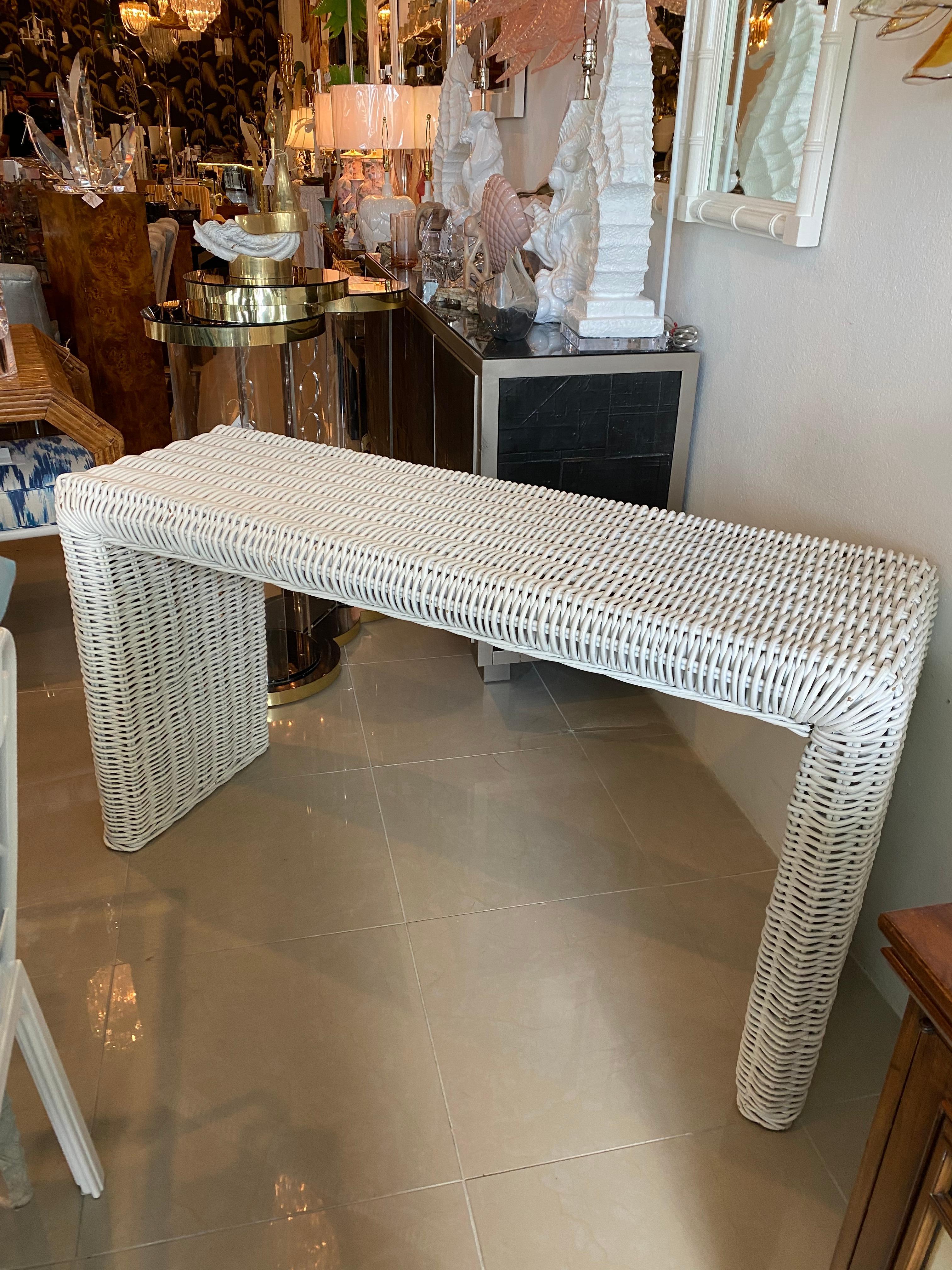 Vintage white wicker, waterfall sides, console table. Original white paint which has a few chippy paint spots. This can be lacquered in color of choice for an additional cost. Dimensions: 30 H x 18 D x 54 L.