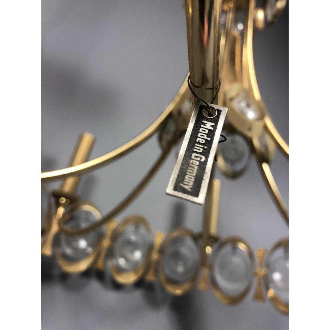 Show-stopping circa 1960s chandelier from German maker Palwa. Brutalist details. Glamorous hanging crystals in a mod disc shape. Six candelabra lights and a central bulb. Cut crystal ceiling plate. Made in Germany metal tag.

The fixture itself is