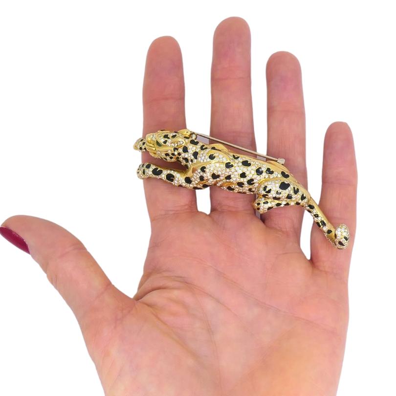A gorgeous vintage panther enamel brooch, crafted of 18k gold, features diamonds, with an emerald accented eye.
The panther's sleek body is adorned with diamonds, creating a beautiful contrast with the glossy black enamel spots. The panther is