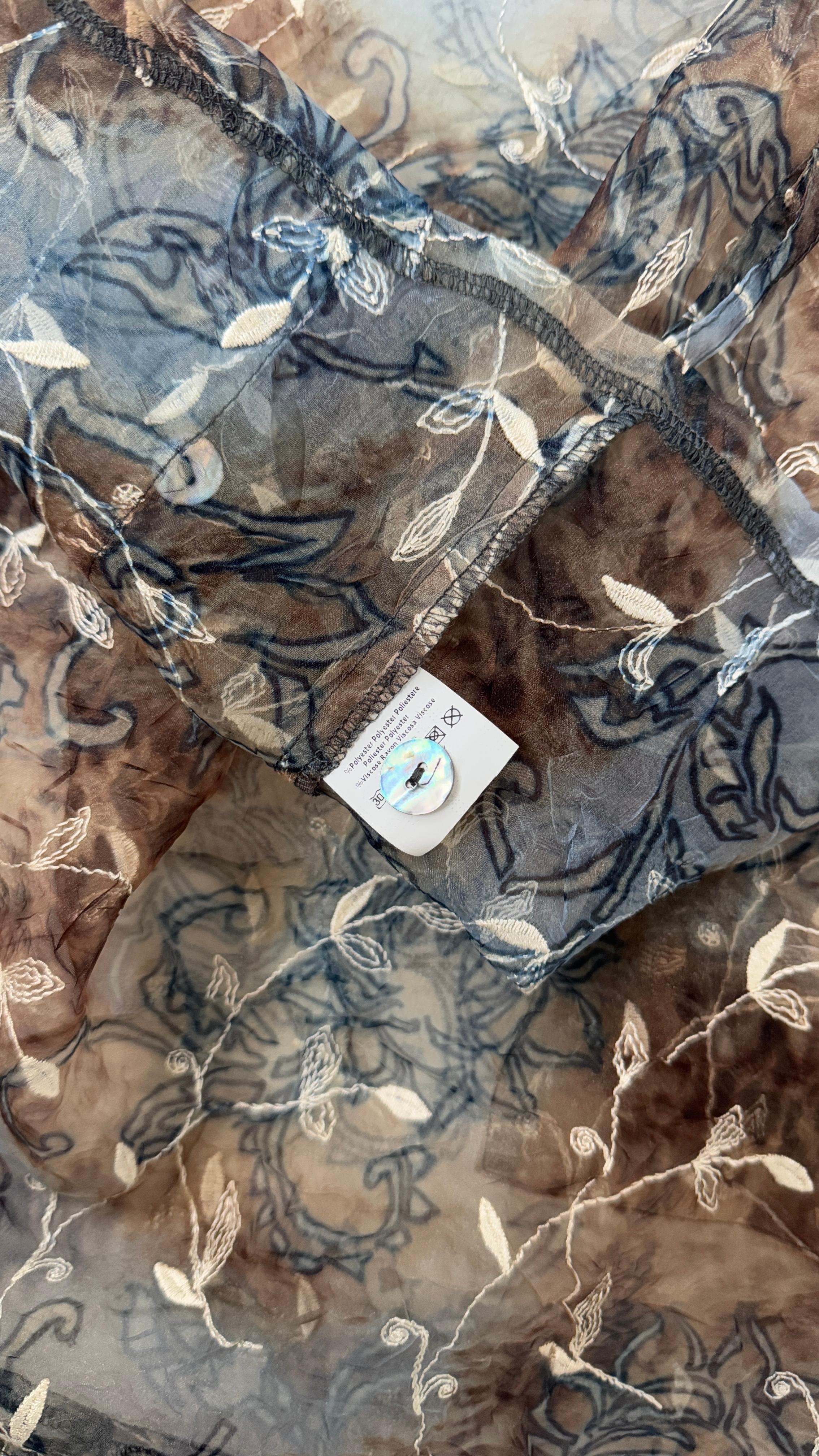 Step into the romantic elegance of the late 1990s with this rare sheer floral shirt by PAP Milano, crafted in Italy. This lightweight, semi-transparent blouse features a delicate floral pattern in earthy tones of brown, cream, and blue, blending