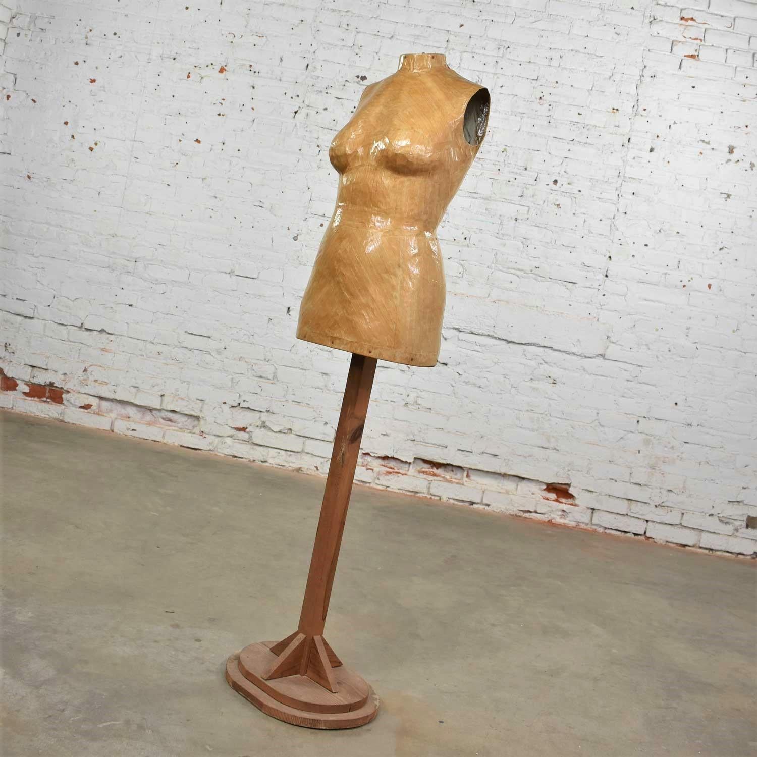 Interesting papier-mâché female dress form mannequin mounted on a pine wood stand. It is in wonderful vintage condition with no outstanding flaws we have seen but having a nice age patina to the unfinished wood. Please see photos, circa mid-20th