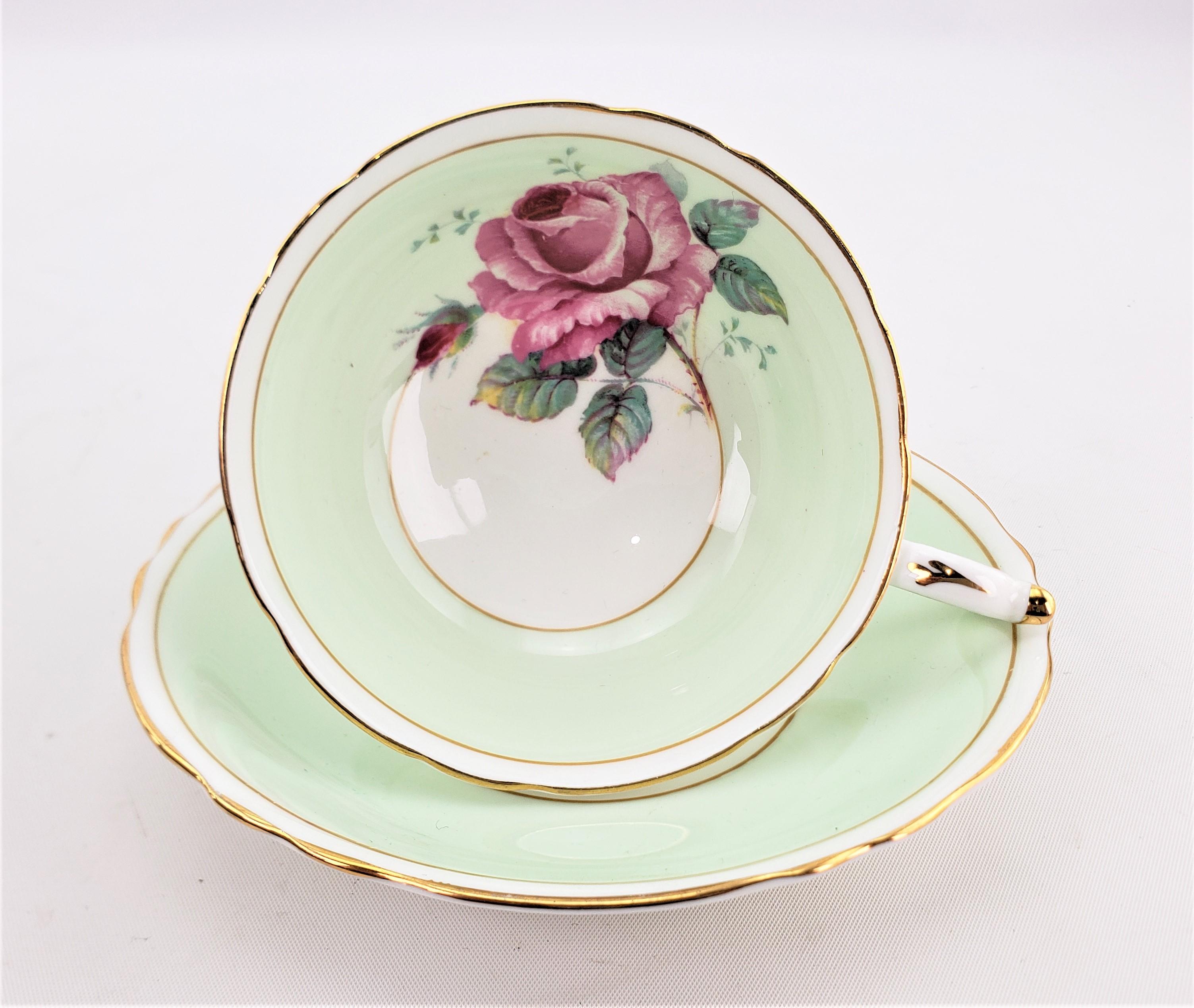 This teacup and saucer set was made by the renowned Paragon fine bone china factory of England in approximately 1960. The set is done with a pastel mint green ground with a large red offset cabbage rose on the inside of the cup which is replicated