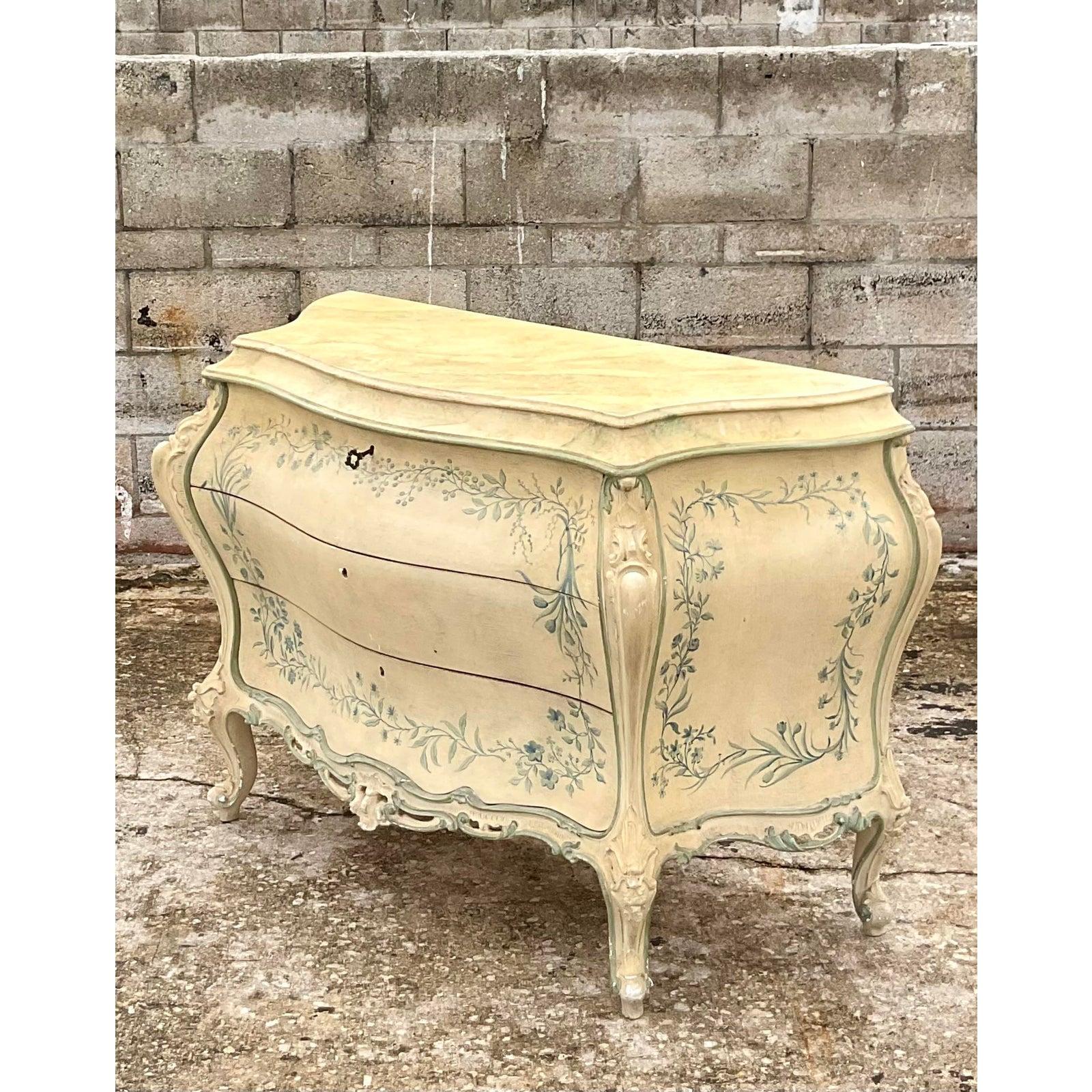 Spectacular vintage Regency hand painted commode. The height of Parisian chic in iconic blue and white. Three drawers that open with a key and beautiful ring of floating flowers. Hand carved detail. Acquired from a Palm Beach estate.