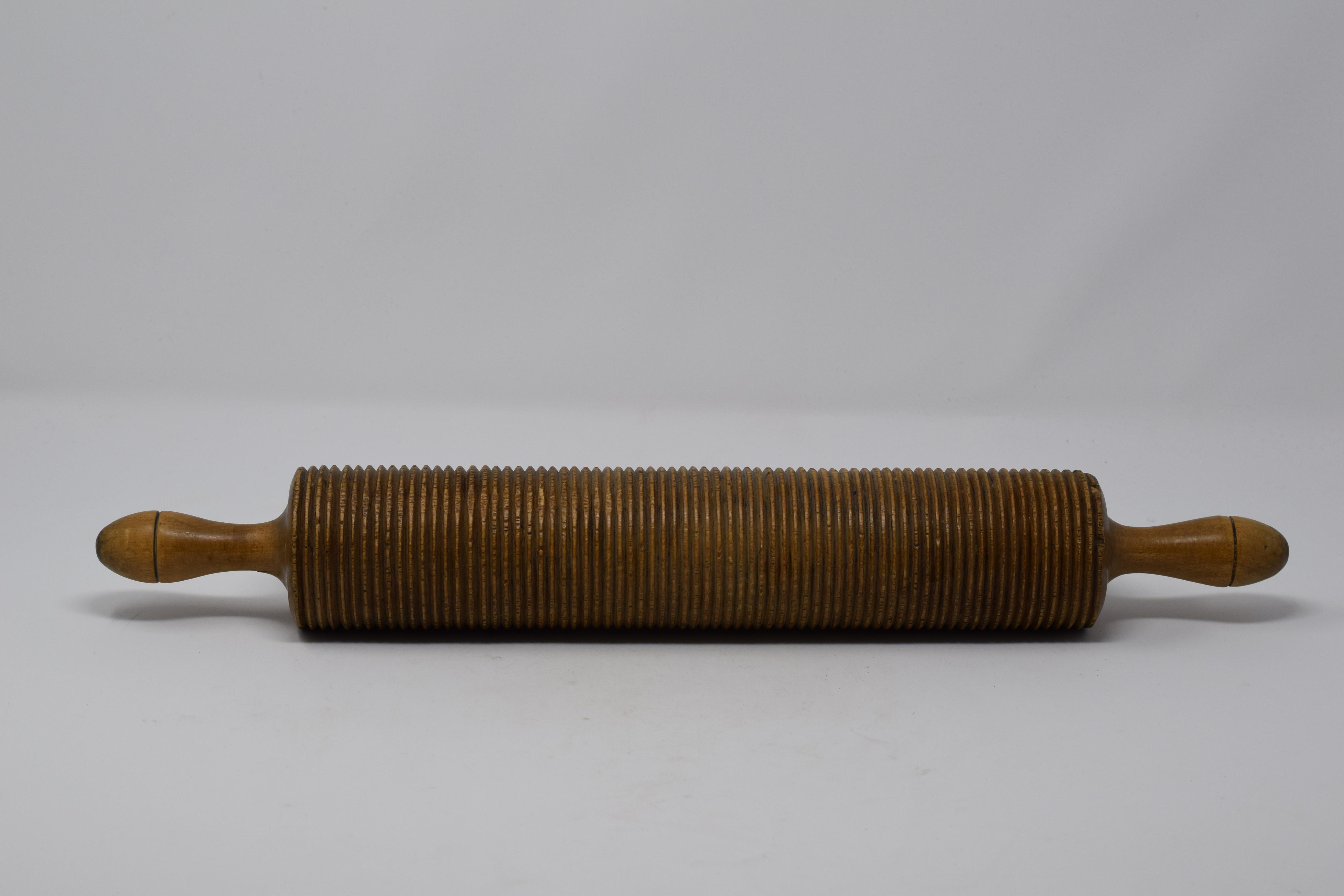 This vintage rolling pin has horizontal ridges and was likely used to make thin spaghetti noodles. The wood pin is in good condition and has a nice worn patina.