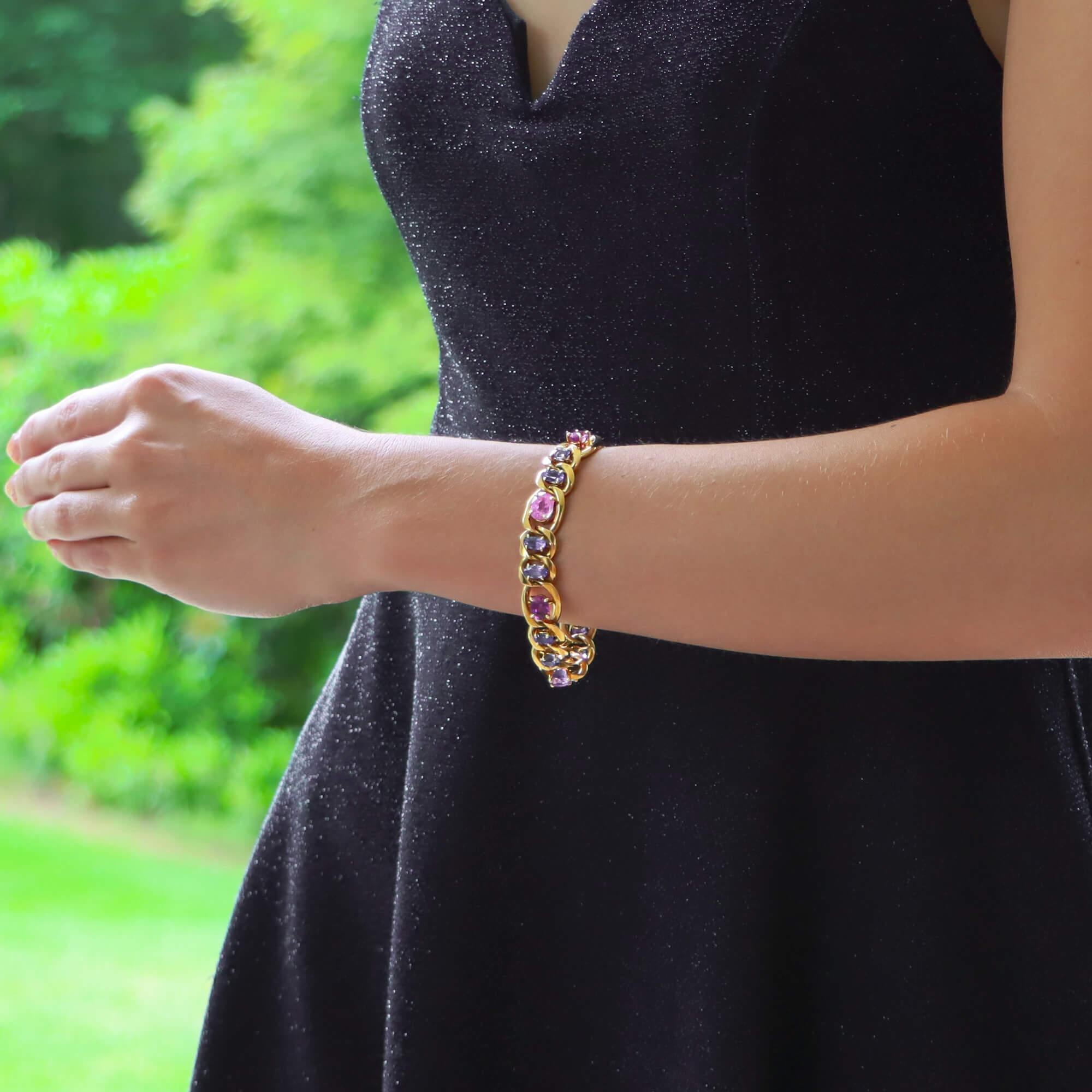 Ein einzigartiges Gliederarmband mit rosa und blauen Saphiren in 18 Karat Gelbgold. 

Das Armband besteht aus achtzehn klassischen, flachen Kettengliedern, die alle in der Mitte entweder mit einem violett-rosa oder blau gefärbten ovalen Saphir