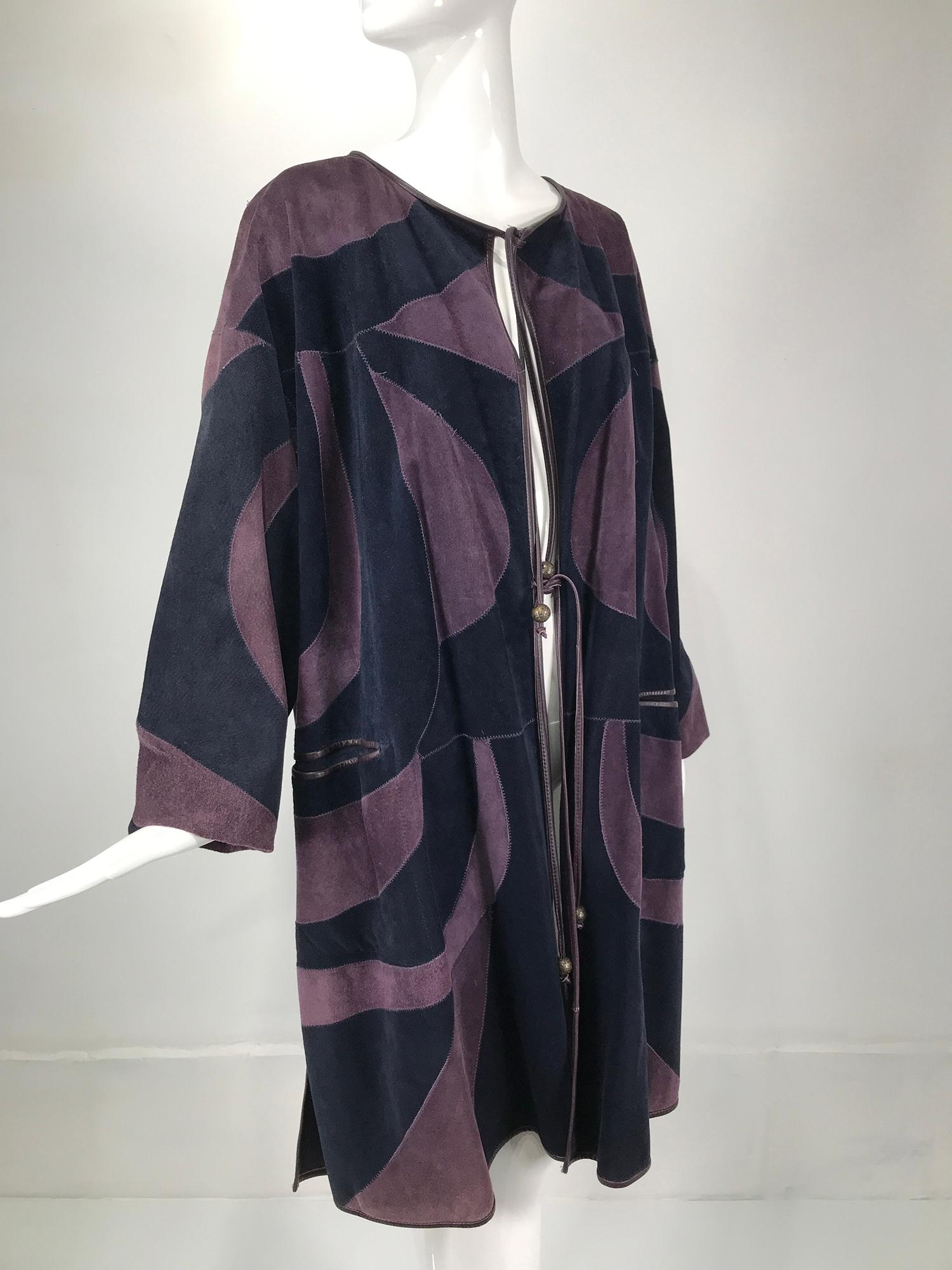 Vintage patchwork suede coat in purple & navy, made in Finland. Open front coat closes with long leather ties at the neck and waist each tie has a silver metallic geometric design bead at the end. The coat facings are trimmed purple leather welt.