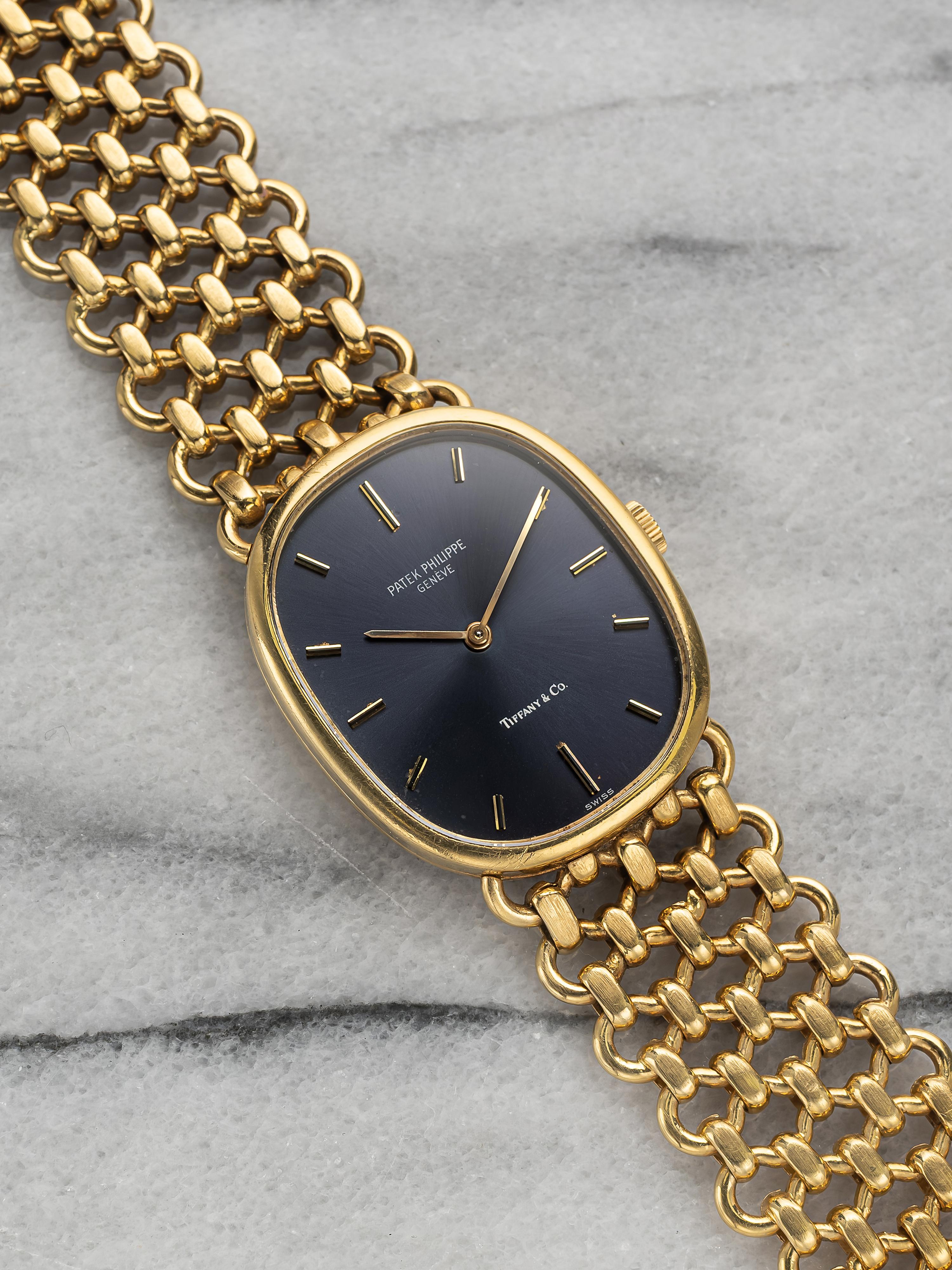 Here's a vintage Patek Philippe Ellipse manual wind in 18K yellow gold with a blue sunburst Tiffany 
Co stamped dial from the 1980s. Keeps great time and is fully functional. Measurements include a 23x28mm case across and an integrated bracelet