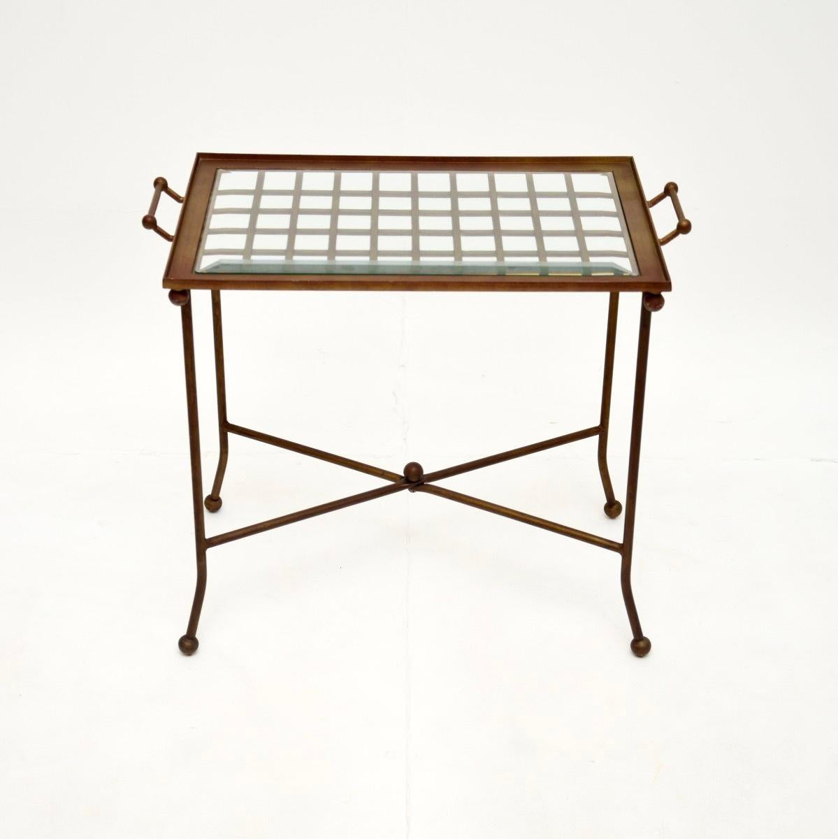 Une table d'appoint vintage élégante en laiton patiné et verre, fabriquée en France et datant des années 1970.

Il est d'une superbe qualité et présente un design utile. La partie supérieure se soulève à l'aide des poignées pour être utilisée comme