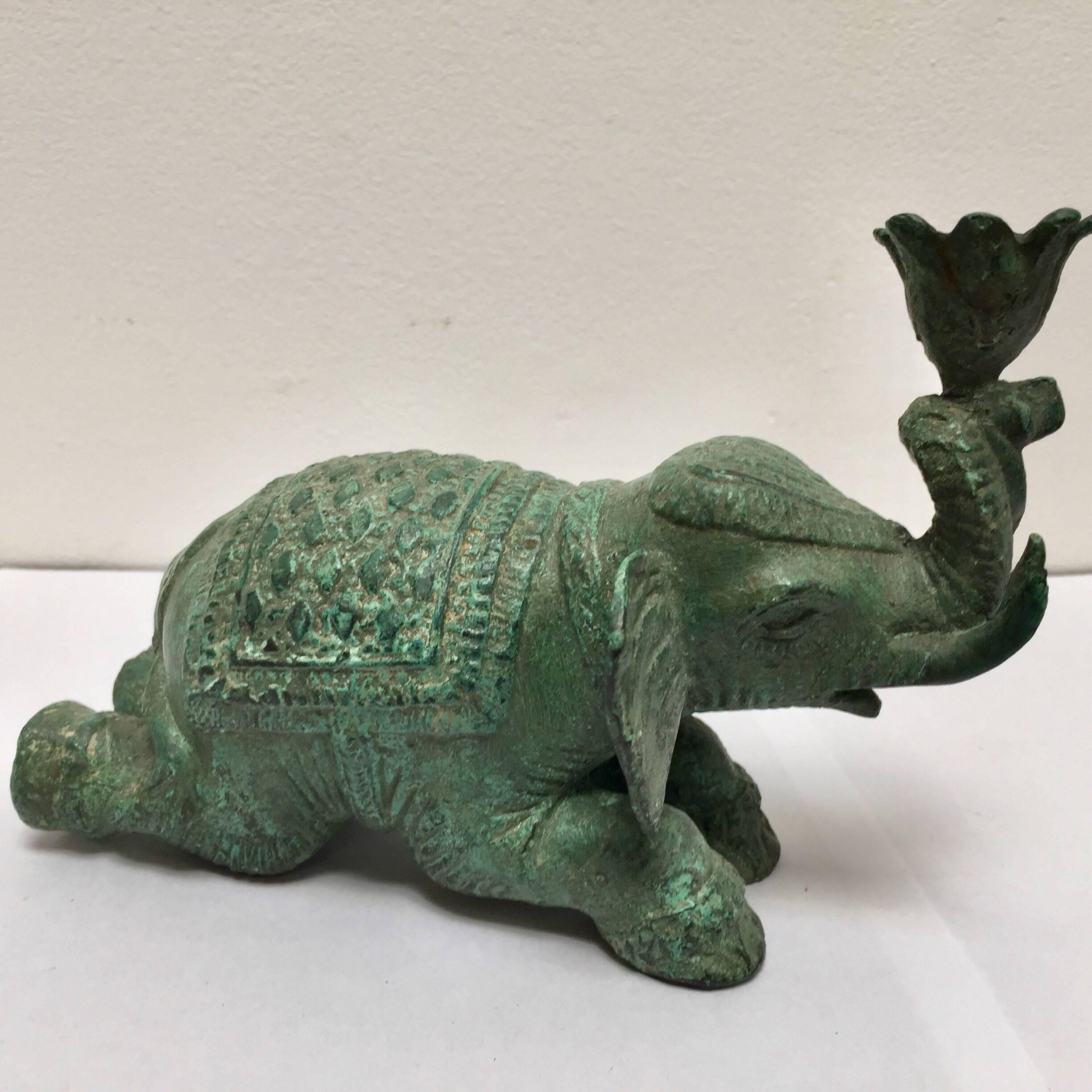 Rajasthani elephant metal sculpture, green bronzed patinated look nicely detailed.
The elephant is shown lying, wearing a ceremonial south Indian patterned blanket on his back as well as decorative florets on his head.
His trunk is up and holding
