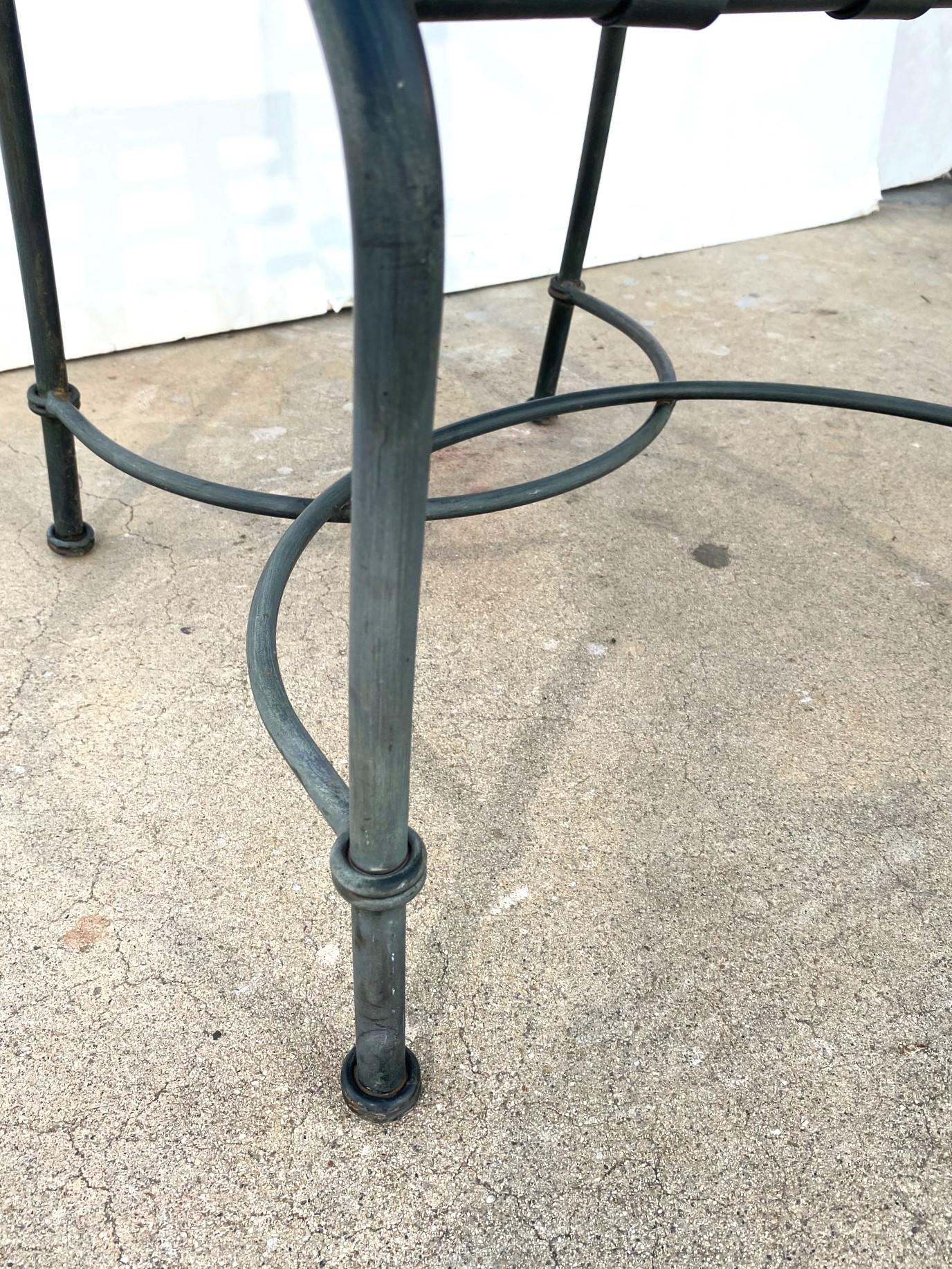Dies ist ein Satz von acht Metall-Terrassensesseln. Die Rückenlehnen und Sitze sind mit Metallgurten versehen, was sie sehr stabil macht. Die Armlehnen sind geschwungen, und die Streckbank verleiht dem Stuhl einen fließenden Charakter.   