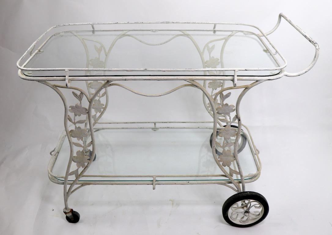 Two-tier serving bar cart, trolley, in old white paint finish. Extremely well made with meticulous attention to detail, specifically the metal frame has a bark like surface, and the leaves and flowers have incised detailing to their surface. The