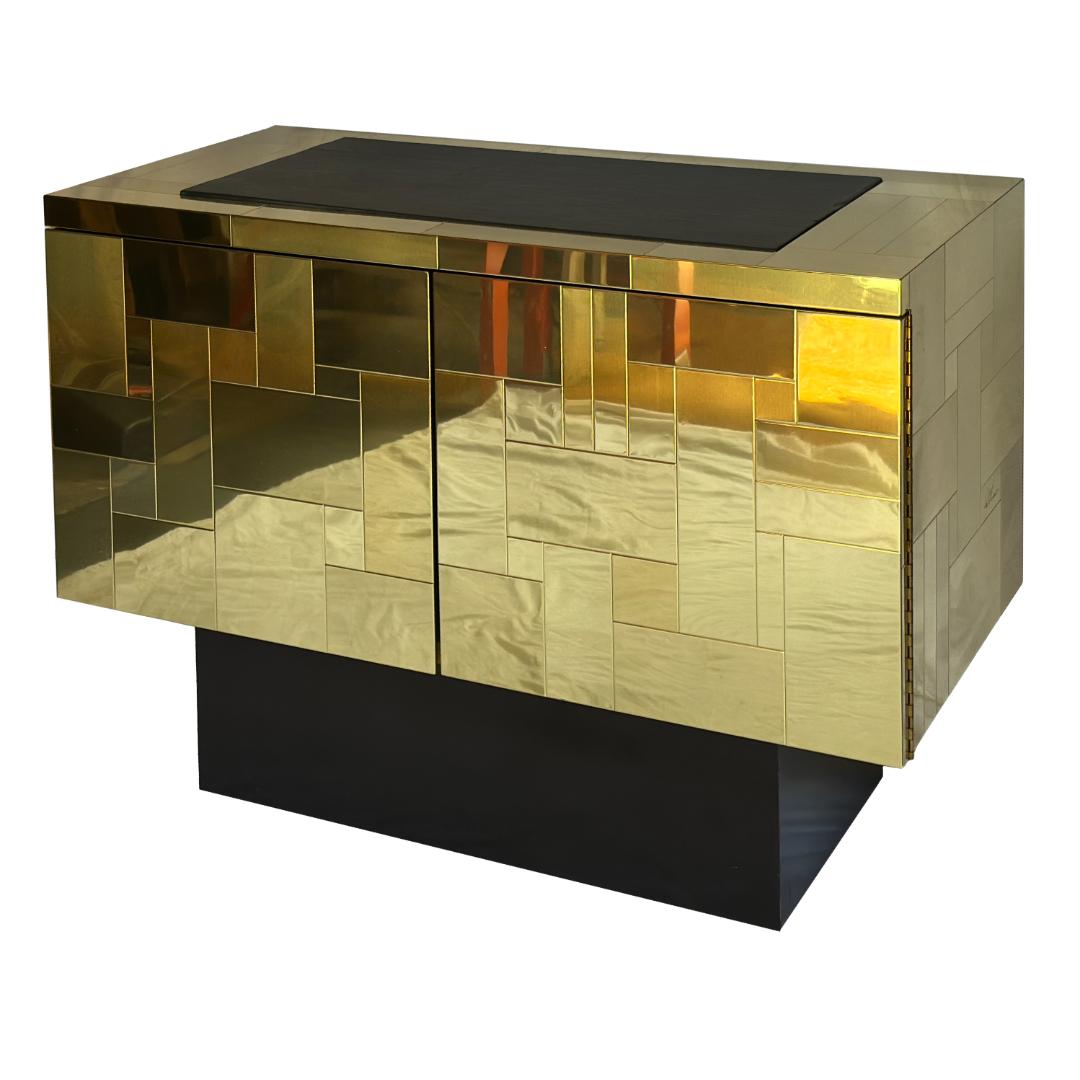 Una sorprendente credenza di metà secolo di Paul Evans per Directional, caratterizzata da una facciata in ottone patchwork, dal suo iconico disegno del paesaggio urbano e da un piano in ardesia. Dietro le due ante con chiusura a pressione si trovano