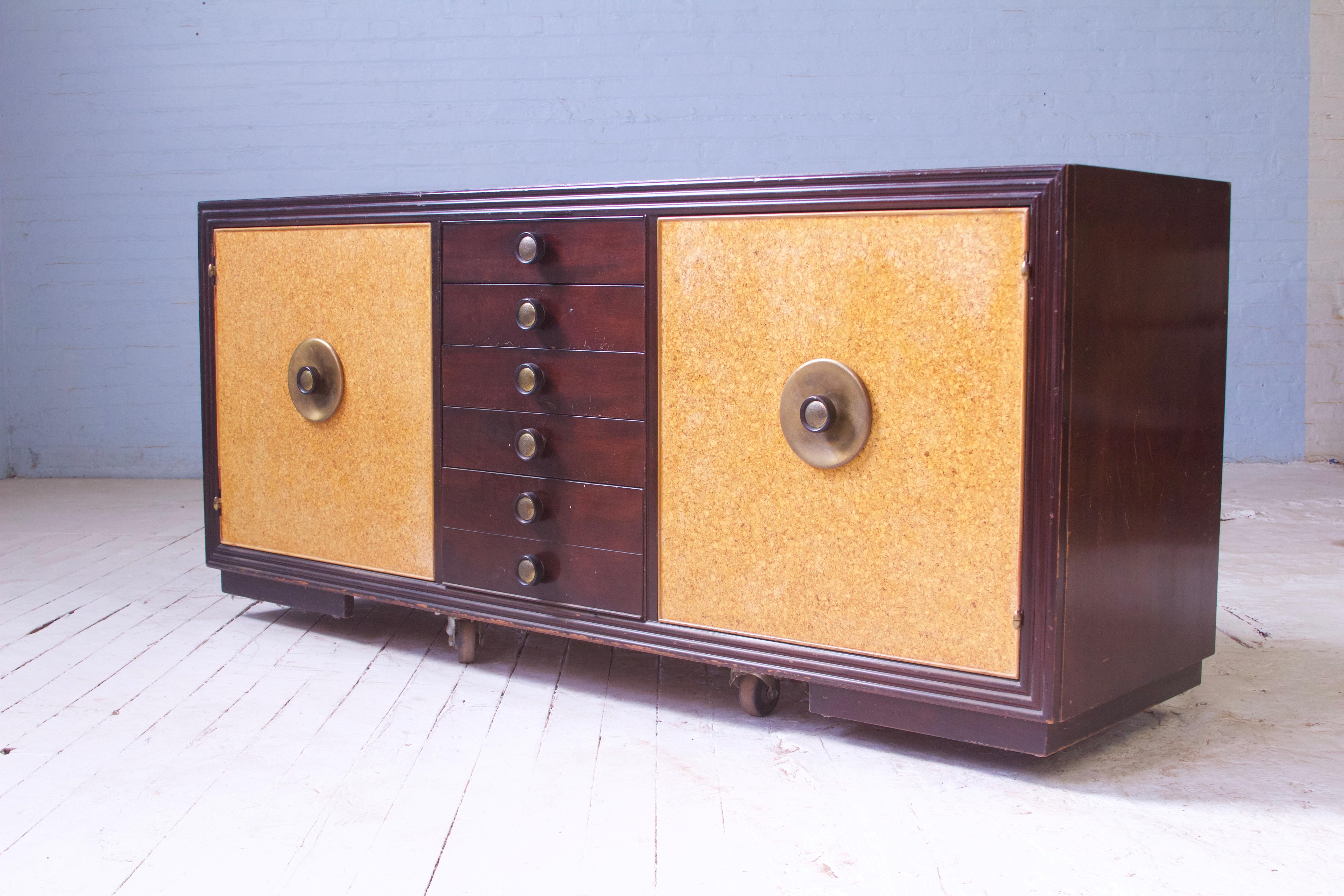 A timeless classic, Paul Frankl for Johnson Furniture Co. sideboard in sculpted mahogany and polished cork with hammered brass hardware. With utility to spare, this piece is comprised of 21 encased drawers, with room and subdivision for all flatware