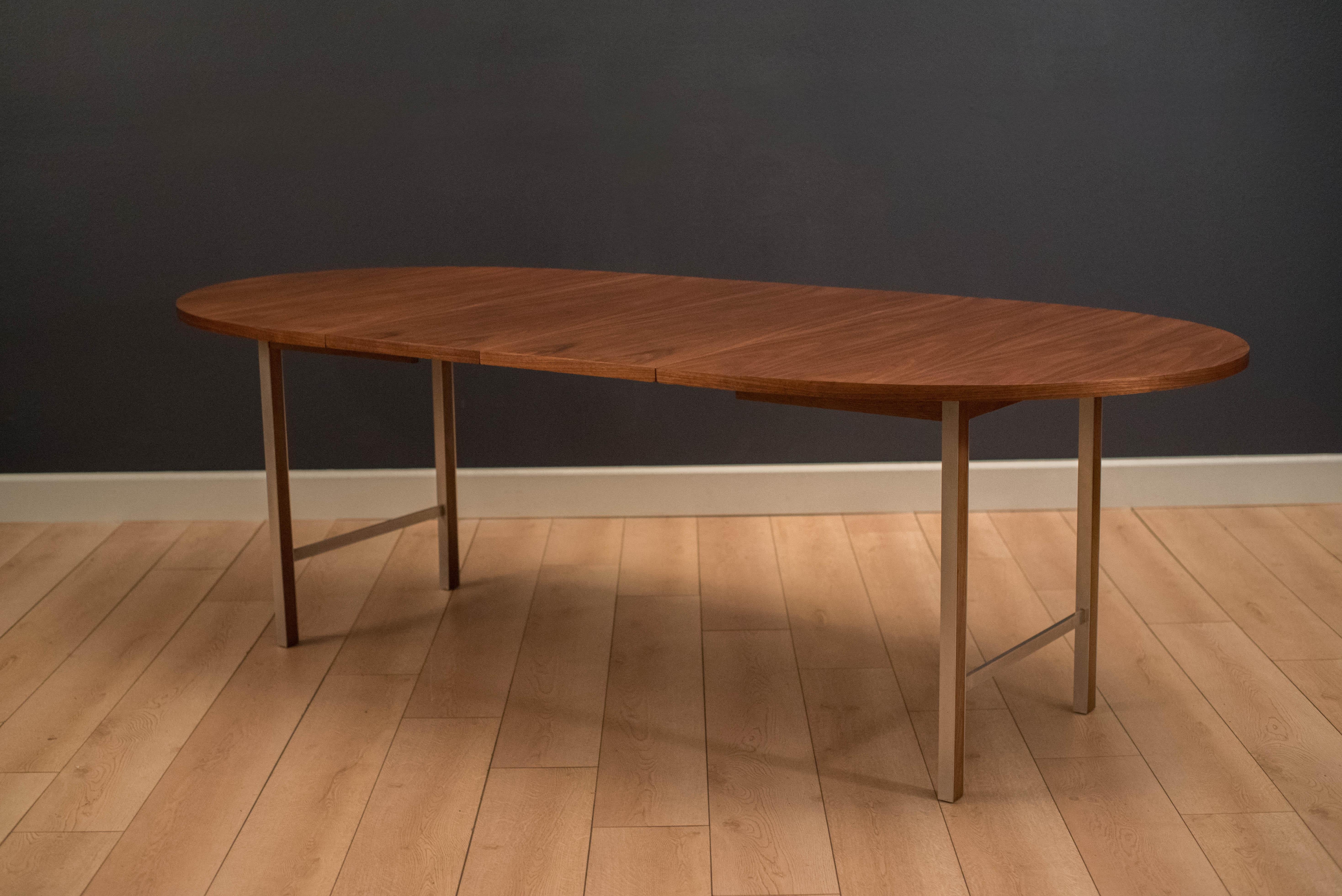 Mid-Century Modern walnut dining table designed by Paul McCobb for the Linear collection of Calvin Furniture. This table has an expansive oval table top and includes two removable leaves. Supporting H-base legs are made of oak and trimmed with