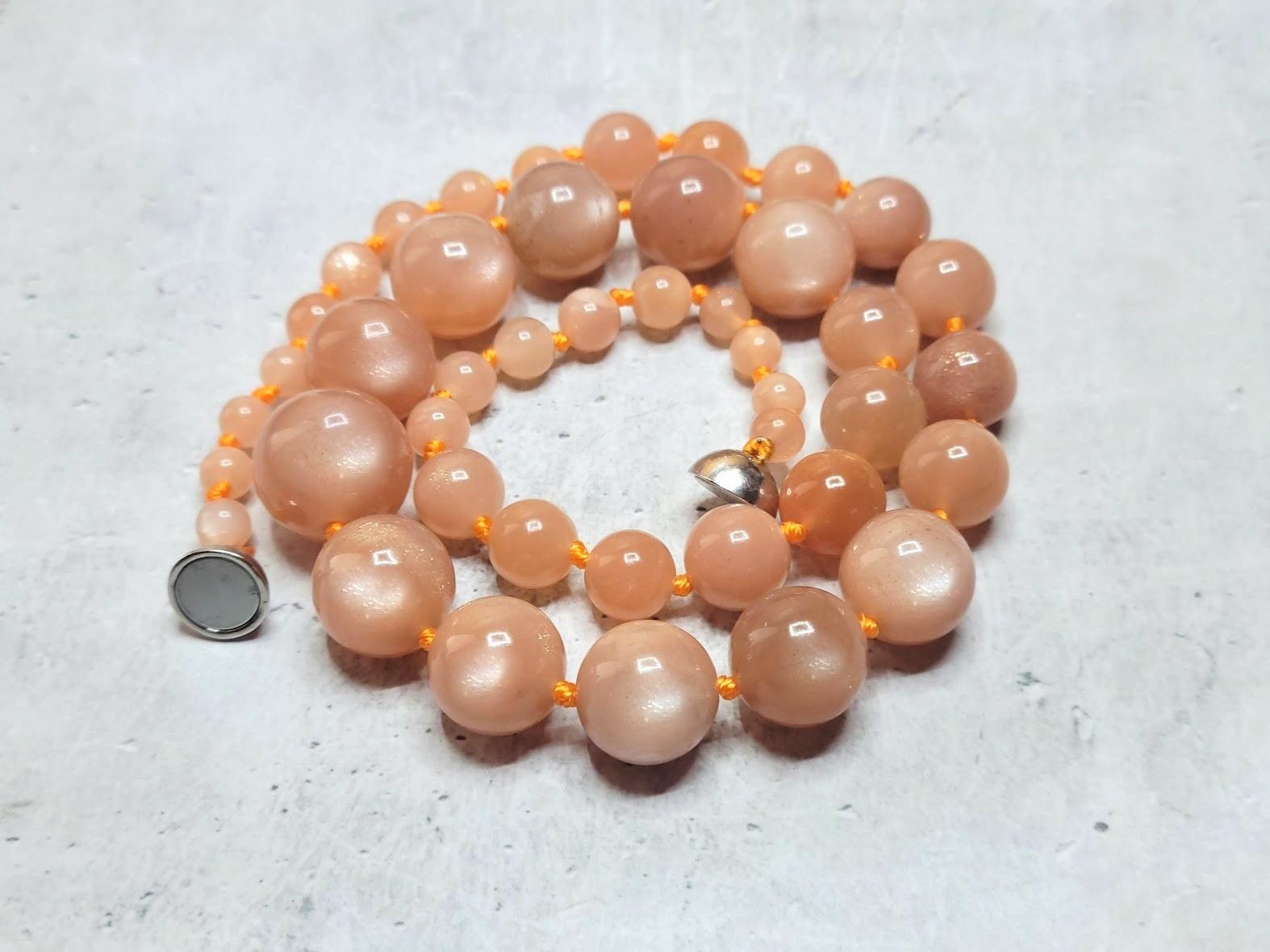 This necklace measures 18.5 inches (47 cm) in length and features smooth round beads ranging from 5 mm to 15 mm in size. The beads have a lovely, soft, and uniform peach tone with a shimmering gold hue. The color is entirely natural, and no thermal