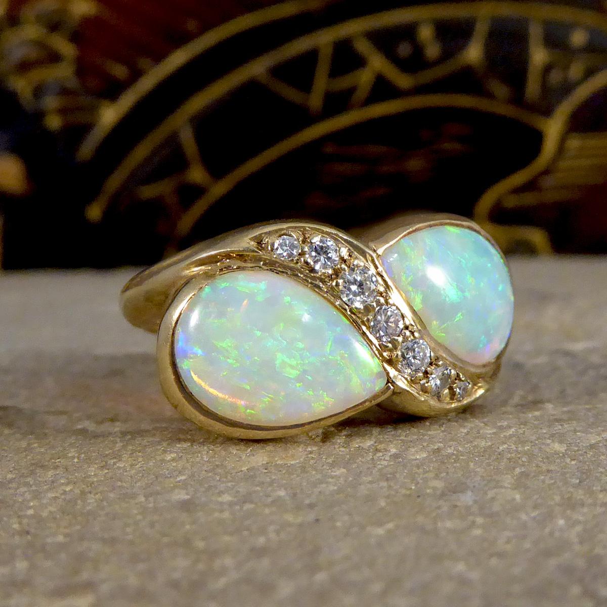 A beautiful vintage twist on a Toi Et Moi style ring. Featuring in this ring are two very bright and colourful Pear cut Diamonds in a rub over setting radiating blues and green with a hint of orange. The two Opals face each other in the centre with