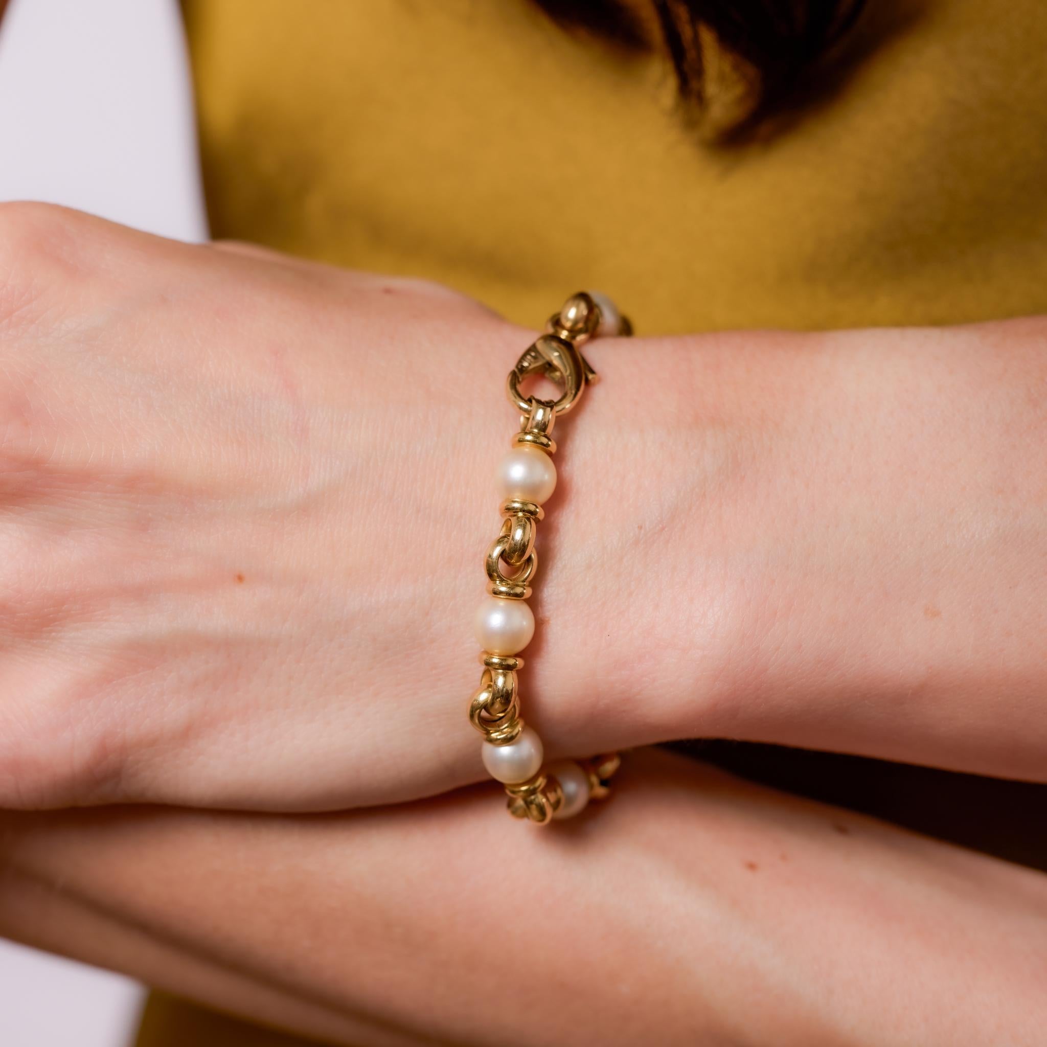 Crafted in the 1980s, this vintage bracelet showcases 10 beautifully matched pearls, each measuring approximately 7.40mm, strung between polished 18k yellow gold links. The soft luster of the pearls contrasts elegantly with the warm gold, creating a