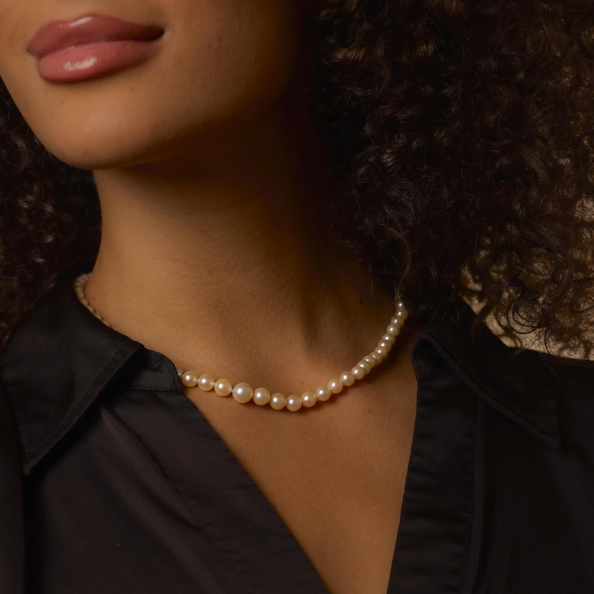 Cet élégant collier vintage des années 1980 présente un rang gradué de soixante-cinq perles lumineuses, d'une taille allant de 4,68 à 8,07 mm. Les perles sont nouées à la main et complétées par un fermoir raffiné réalisé dans un mélange d'or jaune