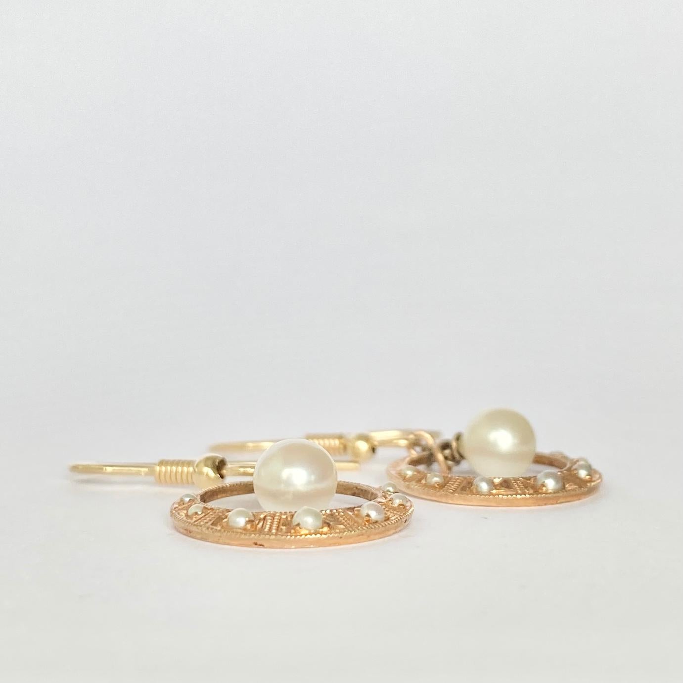These gorgeous pearl drop earrings have a lovely design. They are modelled in 9ct gold and hold a total of seven seed pearls and a large pearl which hangs at the centre of the hoop. 

Drop From Ear: 34mm

Weight: 2.7g