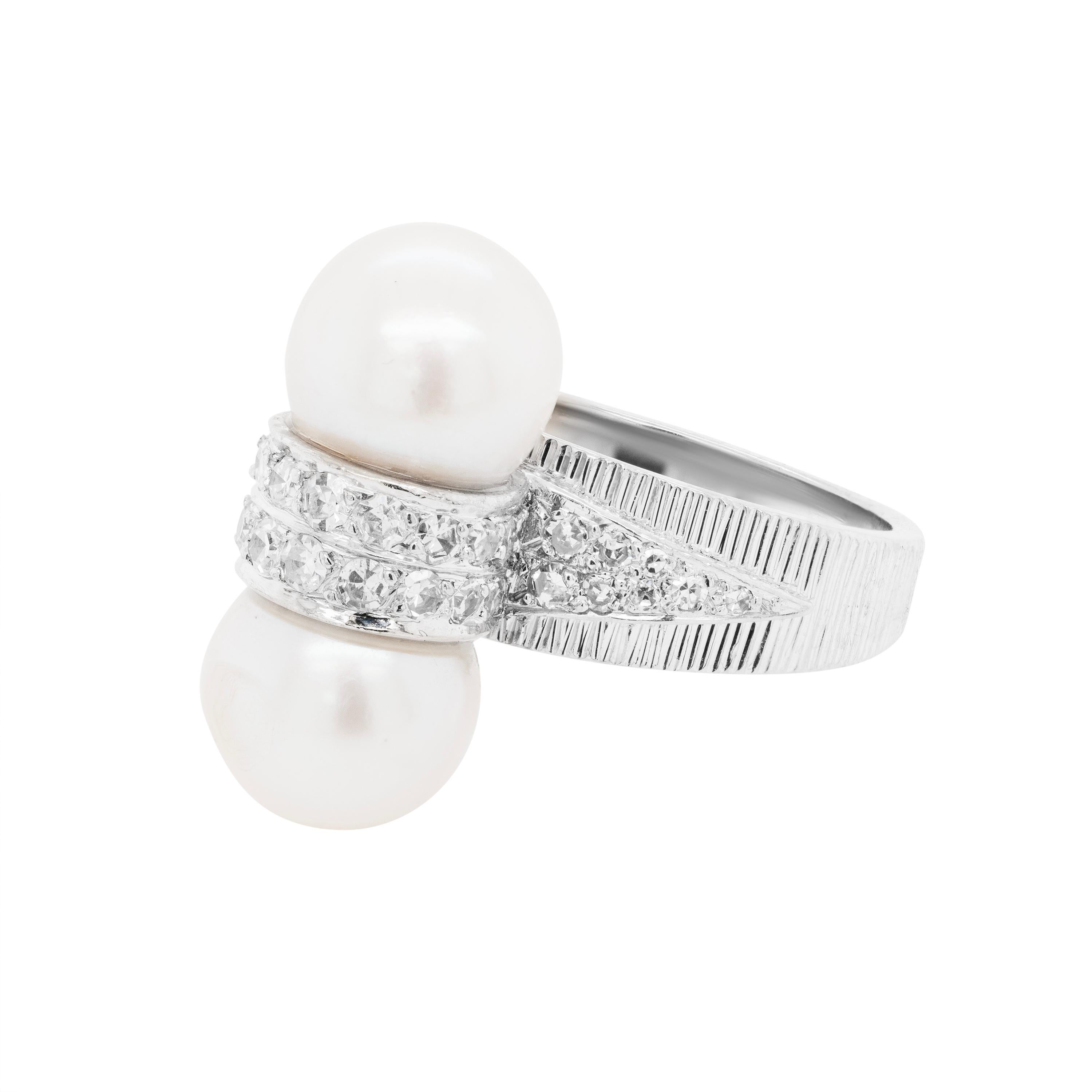 Crafted in 18 carat white gold, this vintage ring features a captivating design, combining the elegance of pearls with the brilliance of diamonds. Two cultured pearls adorn this elegant ring, measuring approximately 9mm each, are mounted above and
