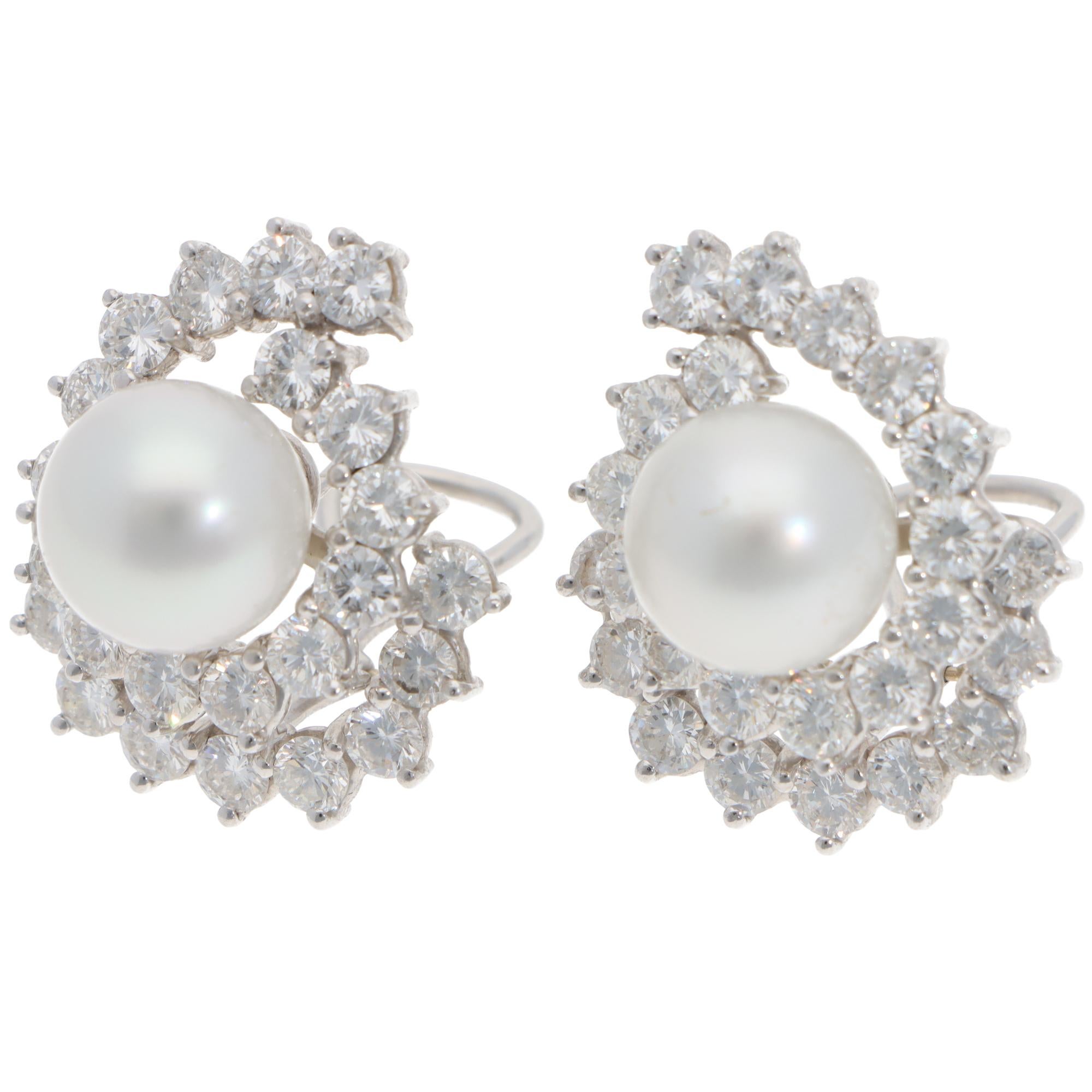 A stunning pair of vintage pearl and diamond stud earrings set in 18k white gold.

The earrings have a beautiful geometric swirl set with 48 round brilliant-cut diamonds. In the centre of the diamonds, there are 2 sizeable white cultured pearls with