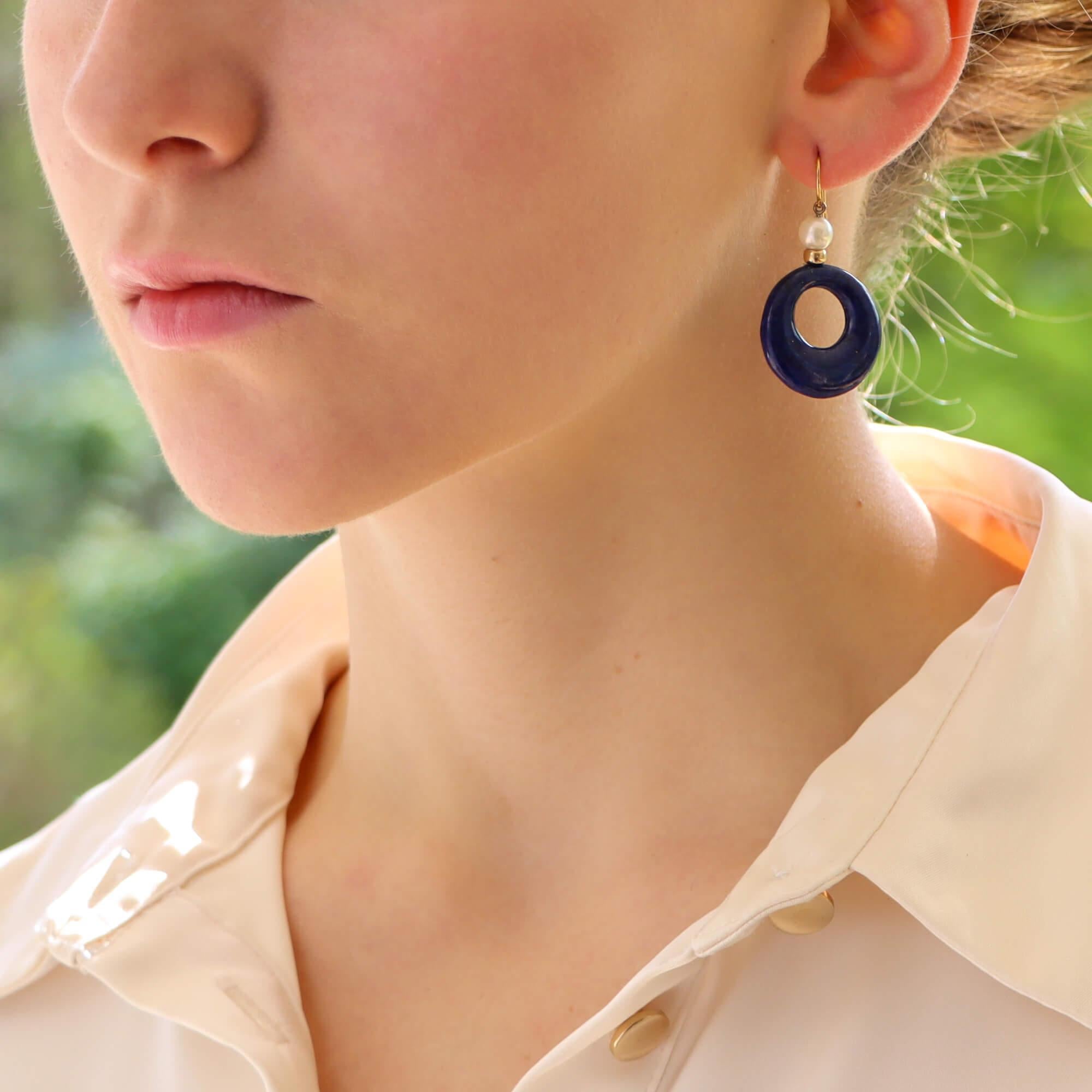  A beautiful pair of pearl and lapis lazuli drop earrings set in 18k yellow gold.

Each earring features a lustrous 6-millimetre white cultured pearl which sits perfectly next to an 18k yellow gold bead. Below this is an impressive carved piece of