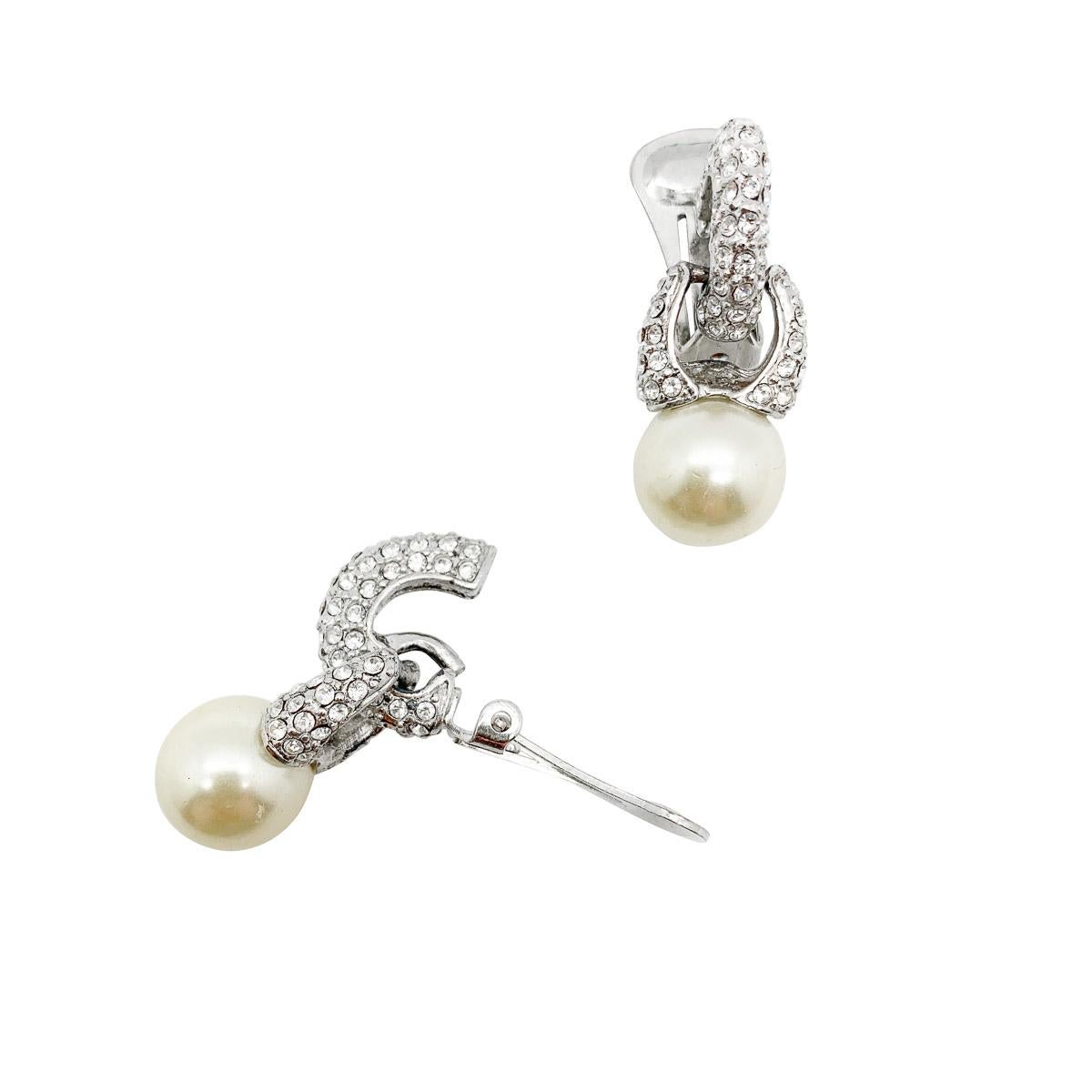 Un par de pendientes vintage de perlas. Con un aro de cristal de estilo abrazador que lleva a una gota de perla adornada con cristales. Una pinza de perlas y cristal perfectamente atemporal que te resultará inestimable.

Estado vintage: Muy bueno