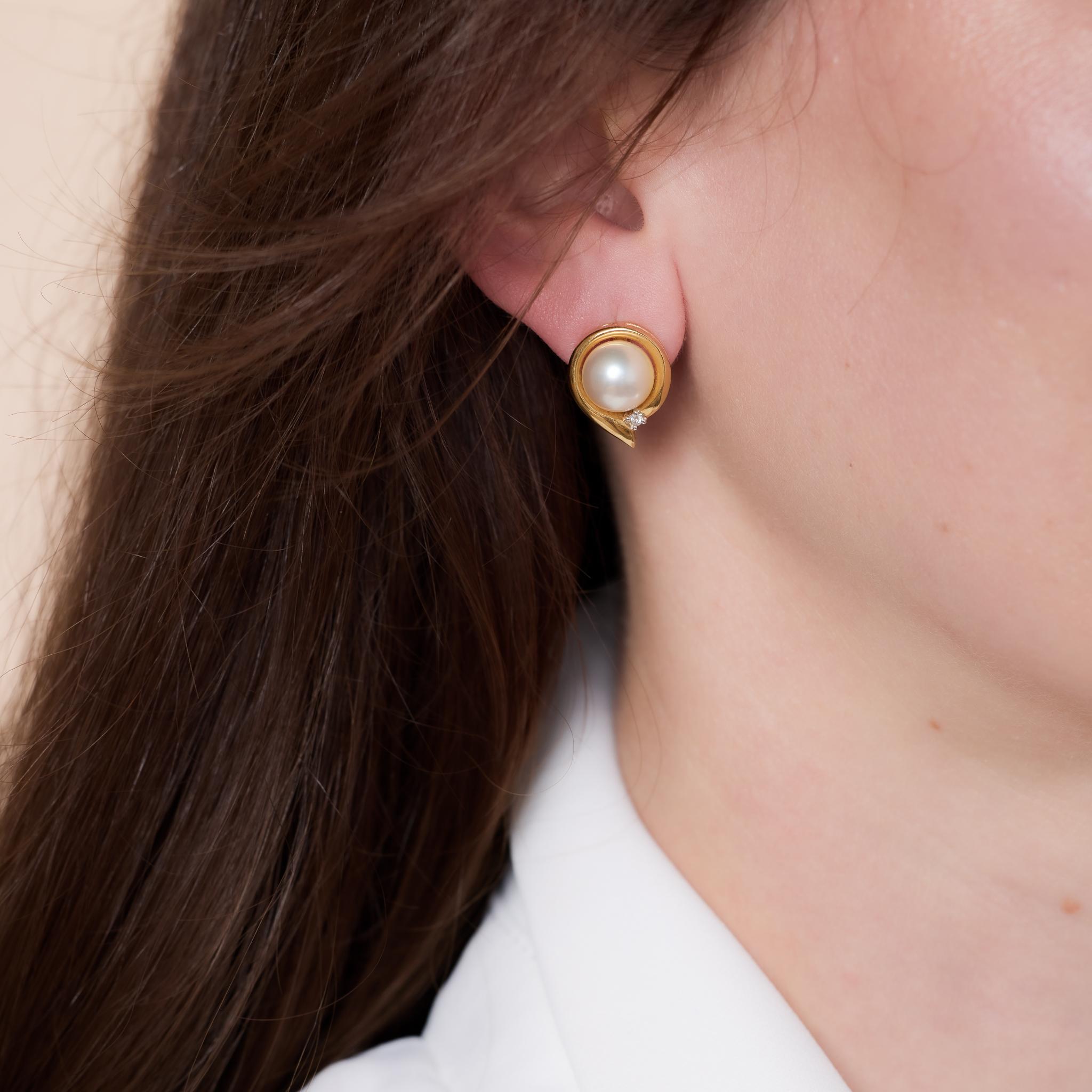 Vintage 18k yellow gold earrings featuring 9mm pearls accented by diamonds, circa 1980s.

Center stone: 2 pearls
Size: 9 mm 
Accent stone: 2 round brilliant cut diamonds
Weight: Approximately .02 carats
Color: E
Clarity: VS
Metal: 18k yellow