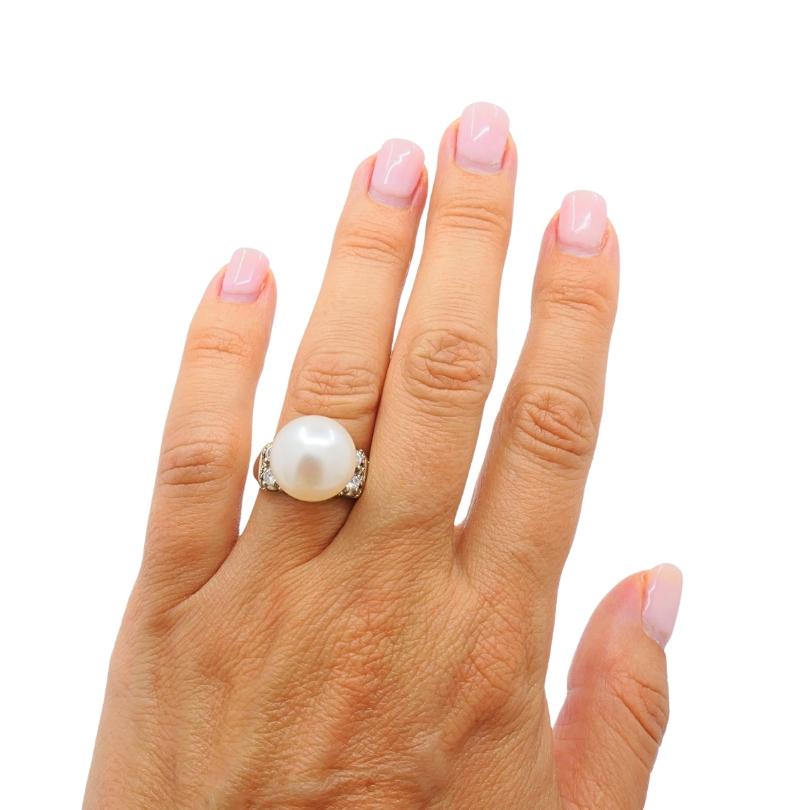 Questo anello vintage è realizzato in oro 14k e progettato con un look audace ed elegante. Al centro si trova una grande perla luminosa che attira immediatamente l'attenzione. La perla è affiancata da file di diamanti a taglio rotondo incastonati