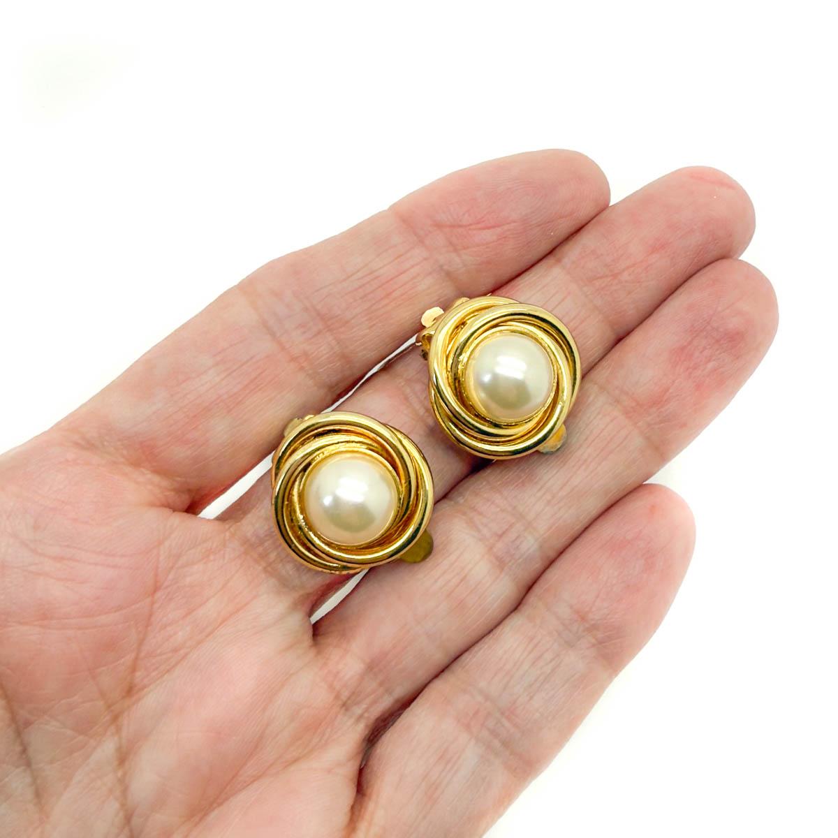 Diese glamourösen Vintage-Ohrringe mit Perlennest strahlen zeitlose Raffinesse aus. Mit ihren schimmernden Perlen, die in reichhaltig vergoldetes Metall gefasst sind, fangen sie die Eleganz vergangener Epochen ein und sind gleichzeitig unbestreitbar