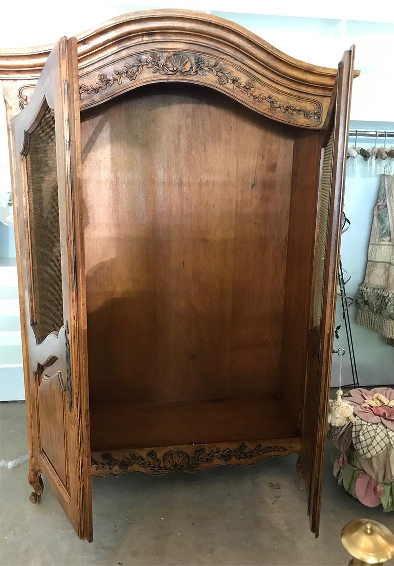 Beautiful carved 2 door Armoire in Pecan. The two doors fully open to reveal 4 shelves. The shelves are removable which makes the use and storage possibilities endless. Traditional shell and floral carved accents adorn the top and bottom front. The