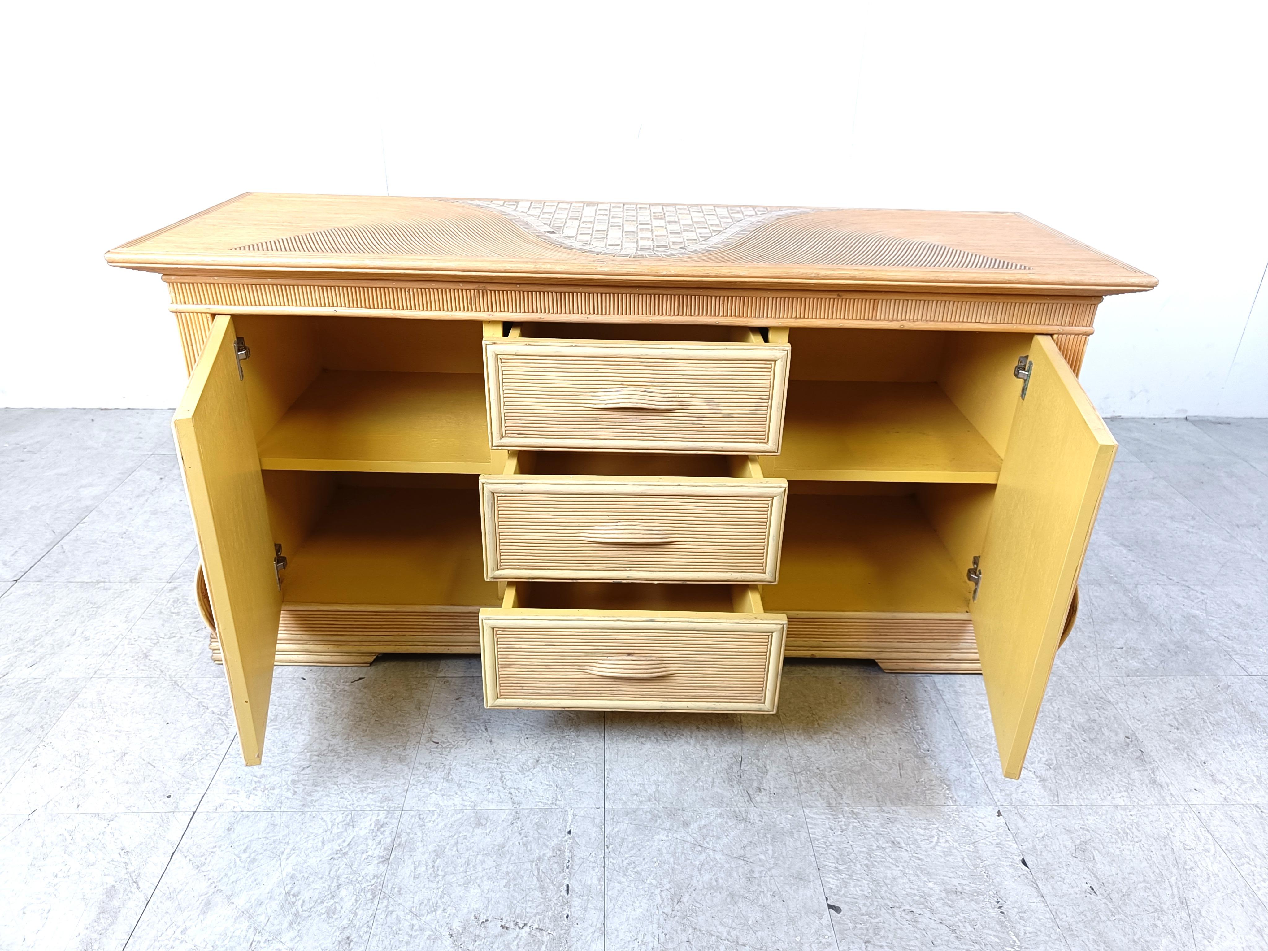 Elegant pencil reed sideboard with 2 doors and 4 drawers

This example is particularly well made with the beautiful bent handles, inlaid ceramic both on top and in the doors and the nice pattern running troughout.

Good condition.

1970s -