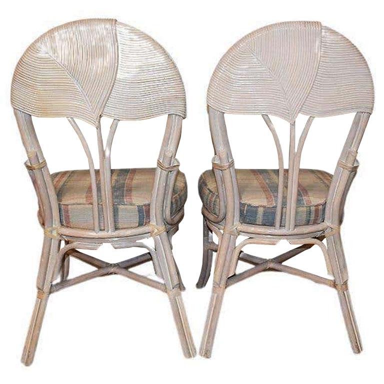 Palm Beach meets Italy with this set of two pencil reed upholstered dining chairs after Gabriella Crespi. Each chair features an overlapping pencil reed back fashioned in the shape of a palm leaf. The legs are rattan-wrapped bamboo and are secured