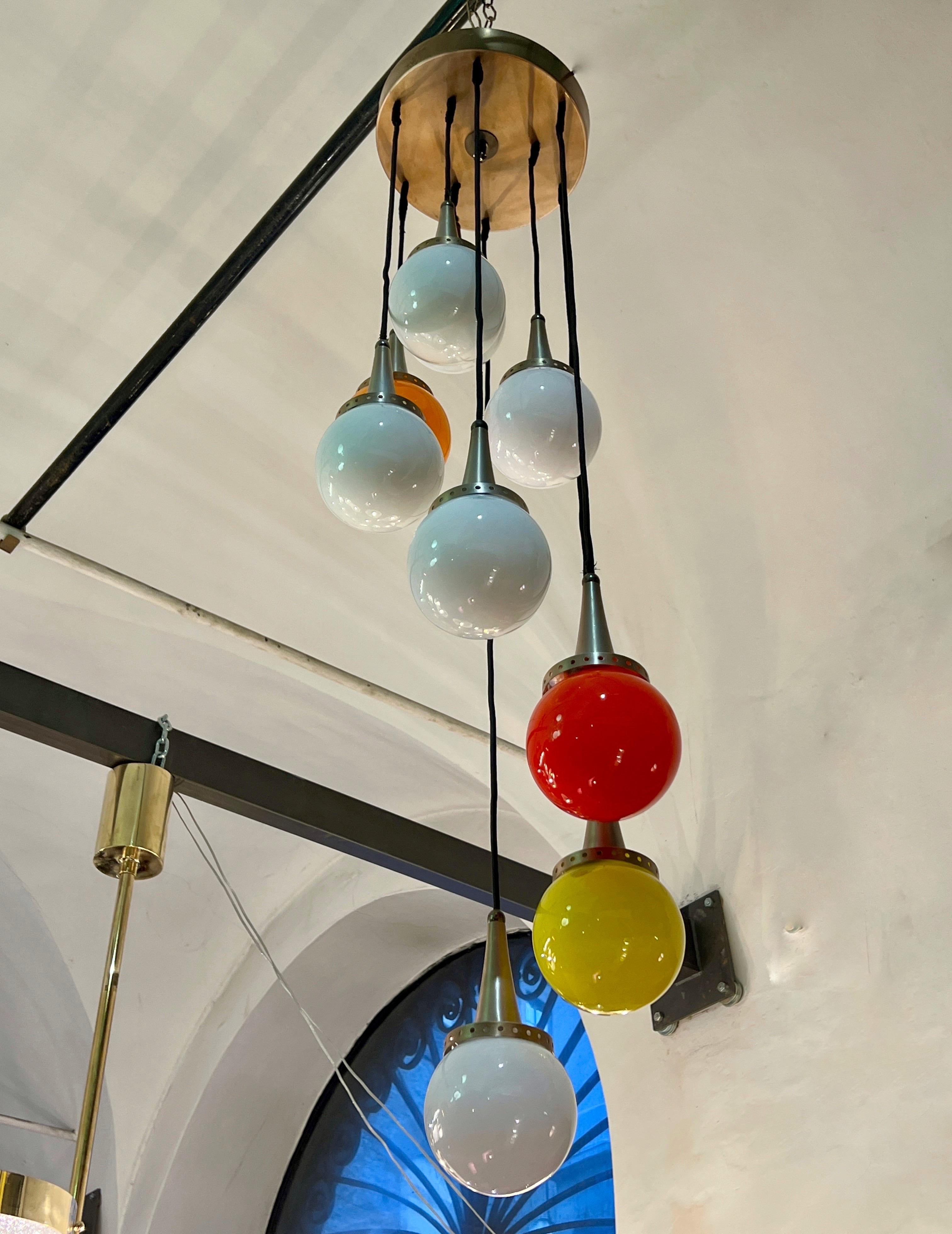 Vintage Pendant Cascade Murano Chandelier 9 lumières attribué à Vistosi, coupelle de plafond en laiton.
Les sphères colorées en verre de Murano sont 6 blanches, une orange, une rouge et une jaune.