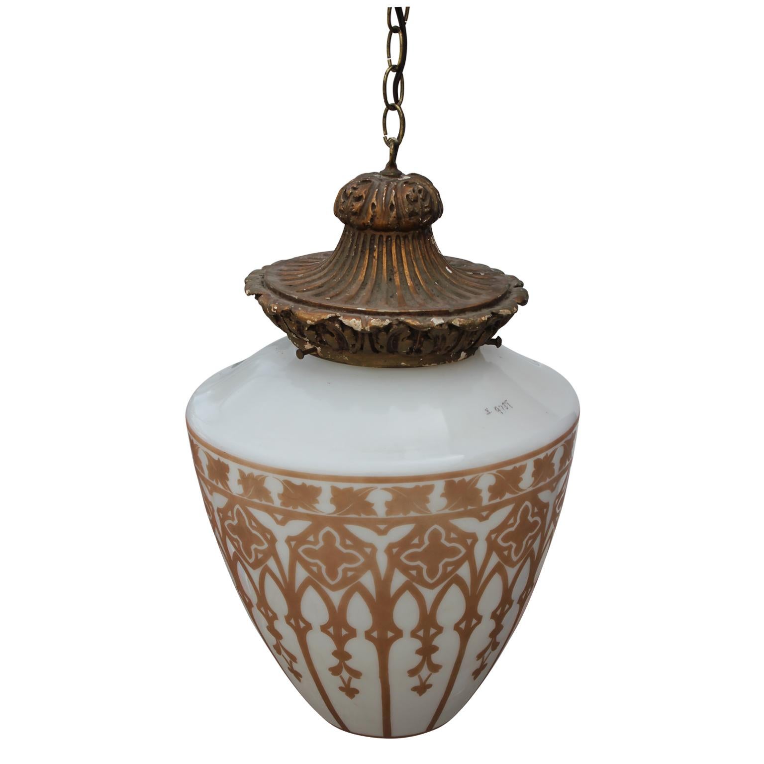 Stately vintage pendant light. It has a gold leafed base that holds the teardrop glass drum. Gold architectural stencils decorate the outside of the white glass, reminiscent of a stained glass window.