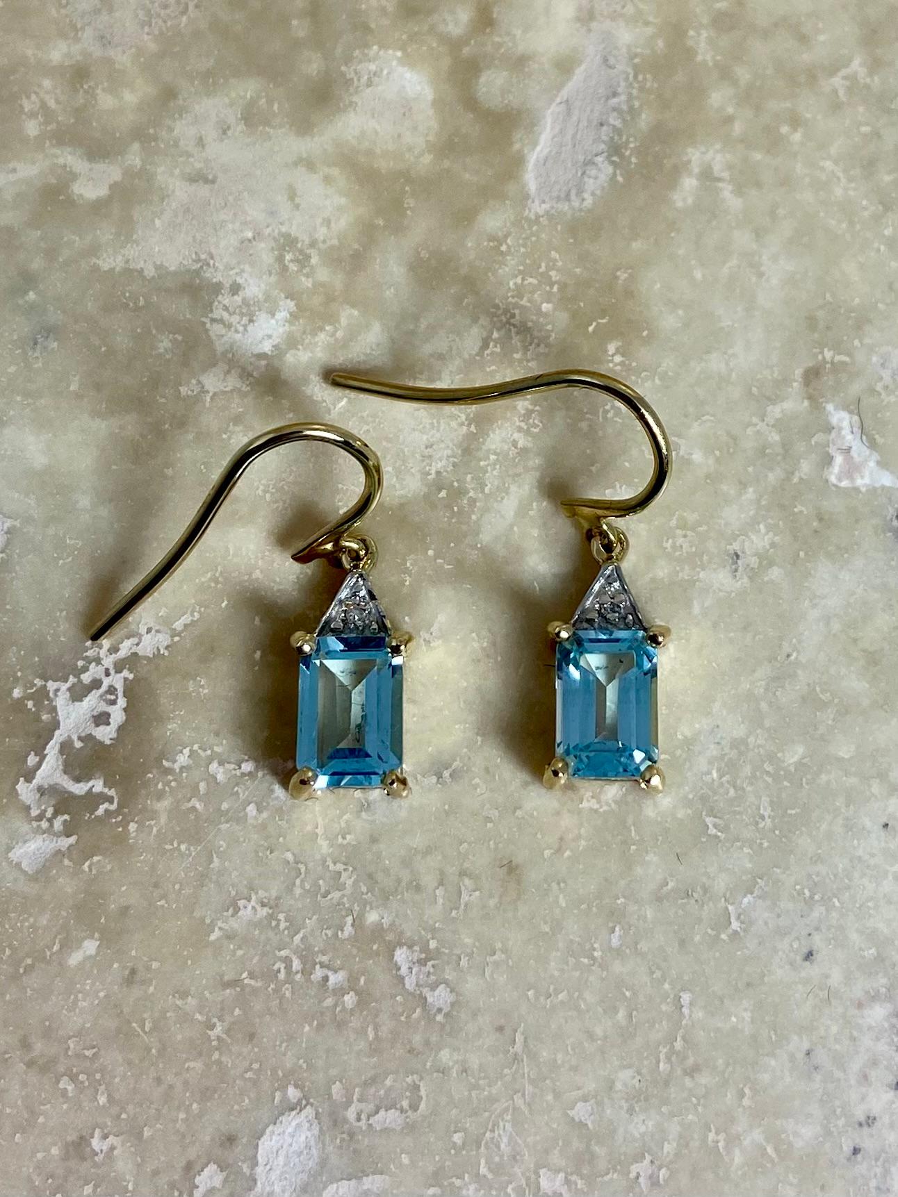 Beautiful and elegant pre-loved  earrings made of 9 carat yellow gold with blue topas. The color blue is truly beautiful and will show bright and vivid in your ears. The topas has an emerald cut with on top diamond stimulant. The height of the