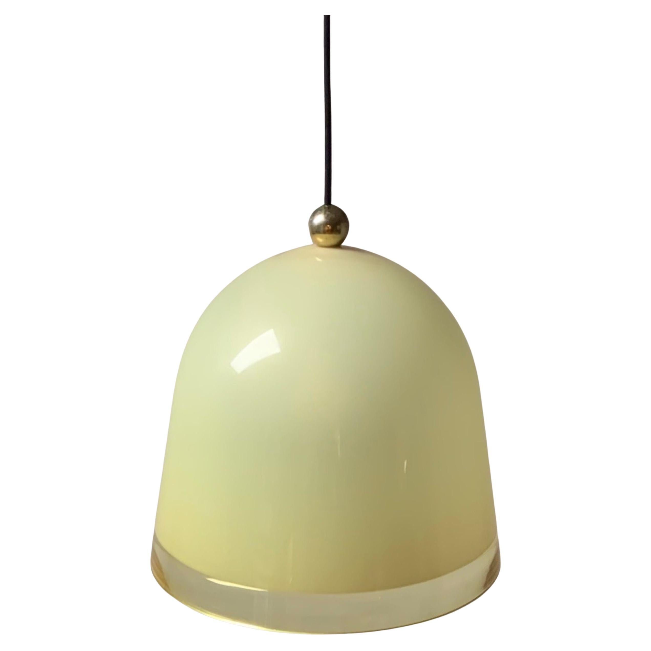 Guzzini Kuala Pendant Lamp was designed by Franco Bresciani in 1975 and produced by iGuzzini from the late 70s until mid 80s. This bell shaped conical lampshade is manufactured with ochre translucent acrylic. It has a chromed metal gold ball on top