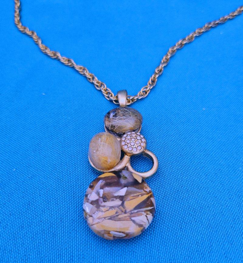 Collana con ciondolo vintage con diverse pietre semipreziose. 
Si tratta di una collana vintage con tre pietre semipreziose, due delle quali sono quarzo rutilato e l'altra crediamo sia mookaite brecciata.  La quarta sfera, la più piccola, è