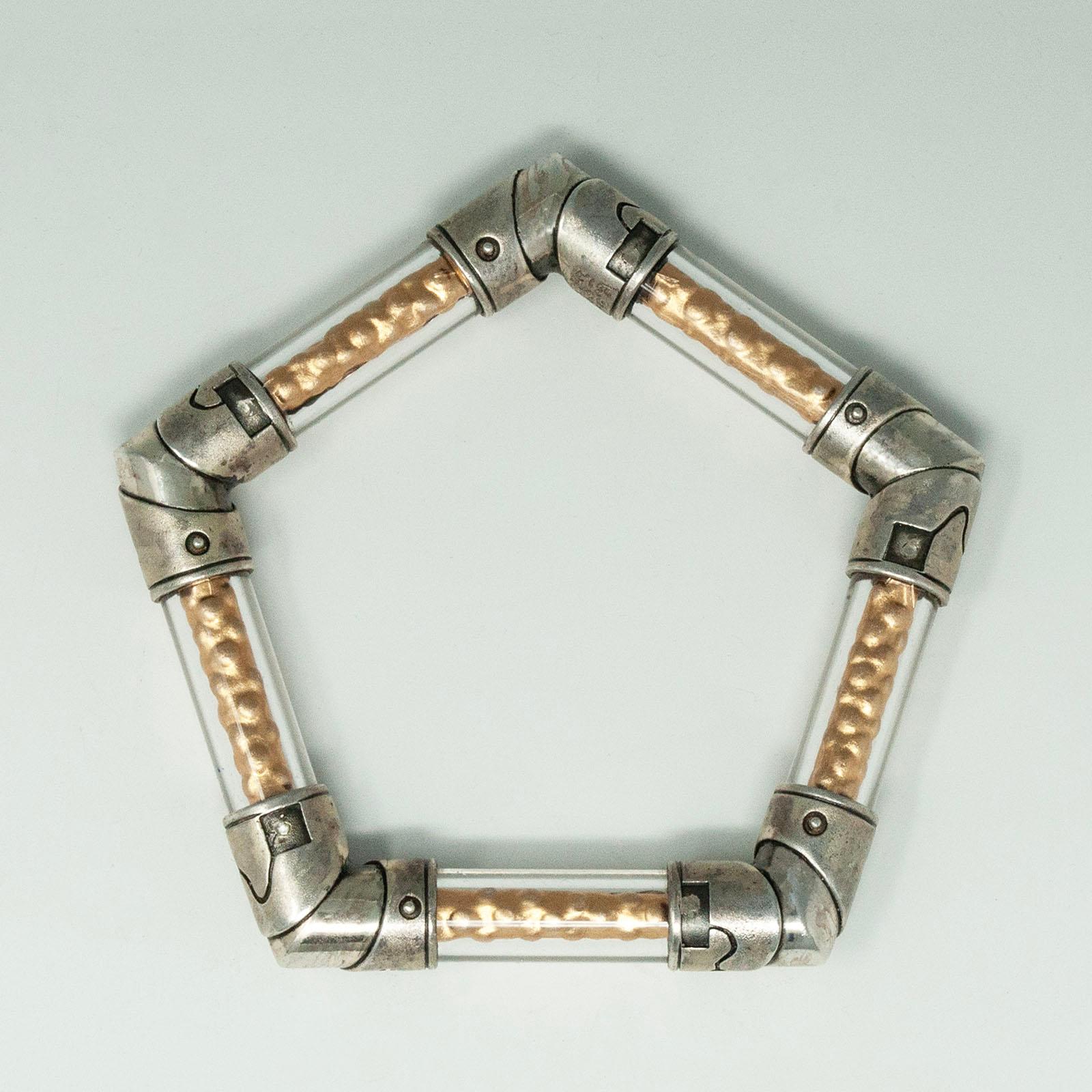 Vintage Pentagon Silver and Acrylic Bracelet

An unusual pentagon-shaped bracelet by Moshe Boster. It is constructed of clear acrylic tubes with hammered golden foil inside, joined at the corners with sterling silver riveted joints - no adhesives