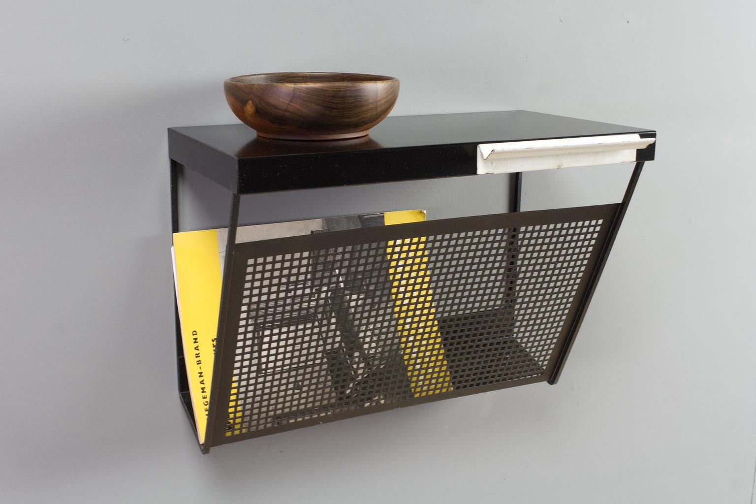 Midcentury Dutch Vintage metal magazine rack in black and white, designed by Tjerk Reijenga for Pilastro, 1960s. The black wall mounted storage rack has a perforated storage compartment for magazines, letters or other post, a small drawer for keys