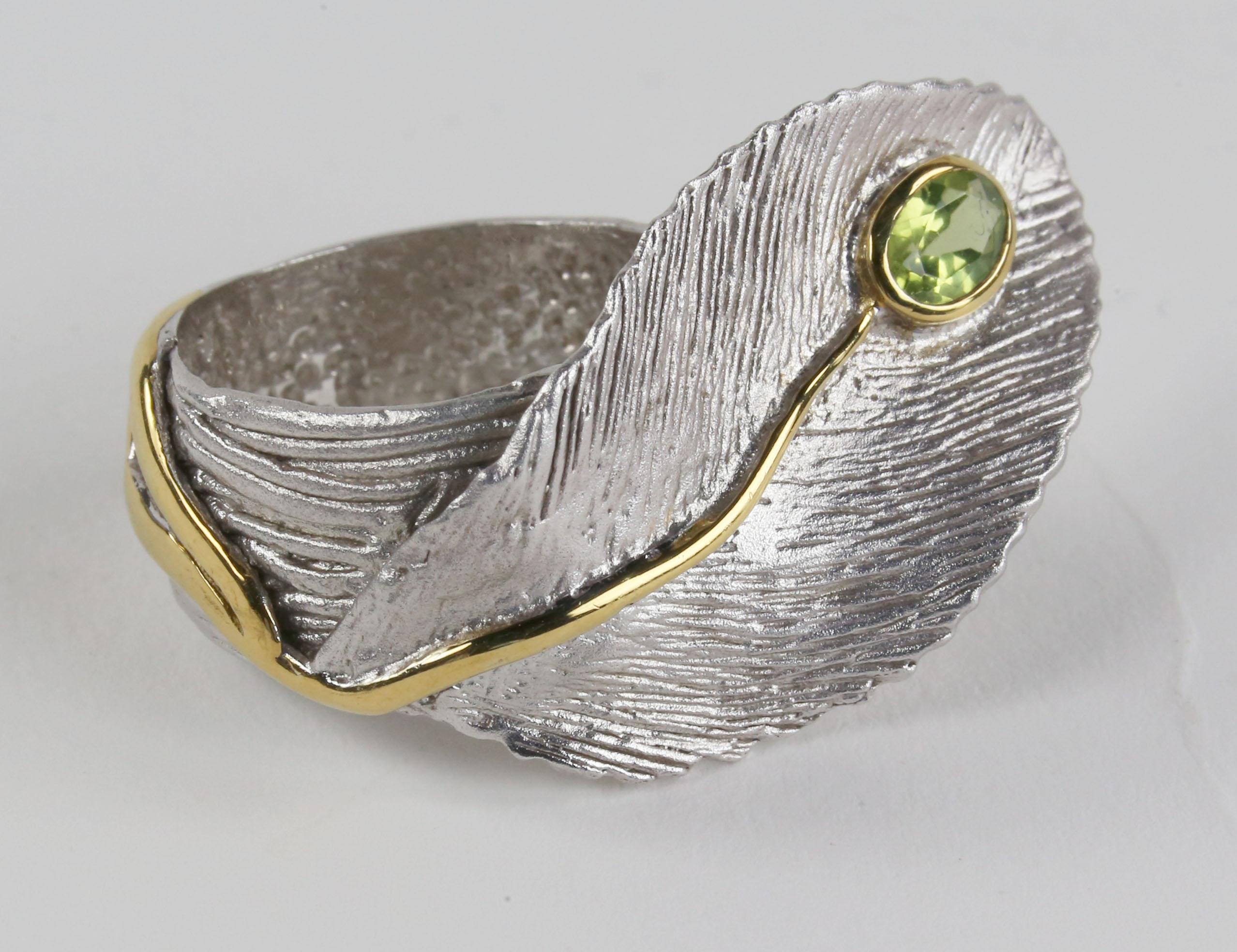 Dynamic and Stylish crafted in Rhodium tarnish resistant Sterling Silver with 14k yellow gold accents. The ring makes a nice statement with its textured design and Peridot Gem Stone setting with 14K yellow Gold stem design accents. The ring is in