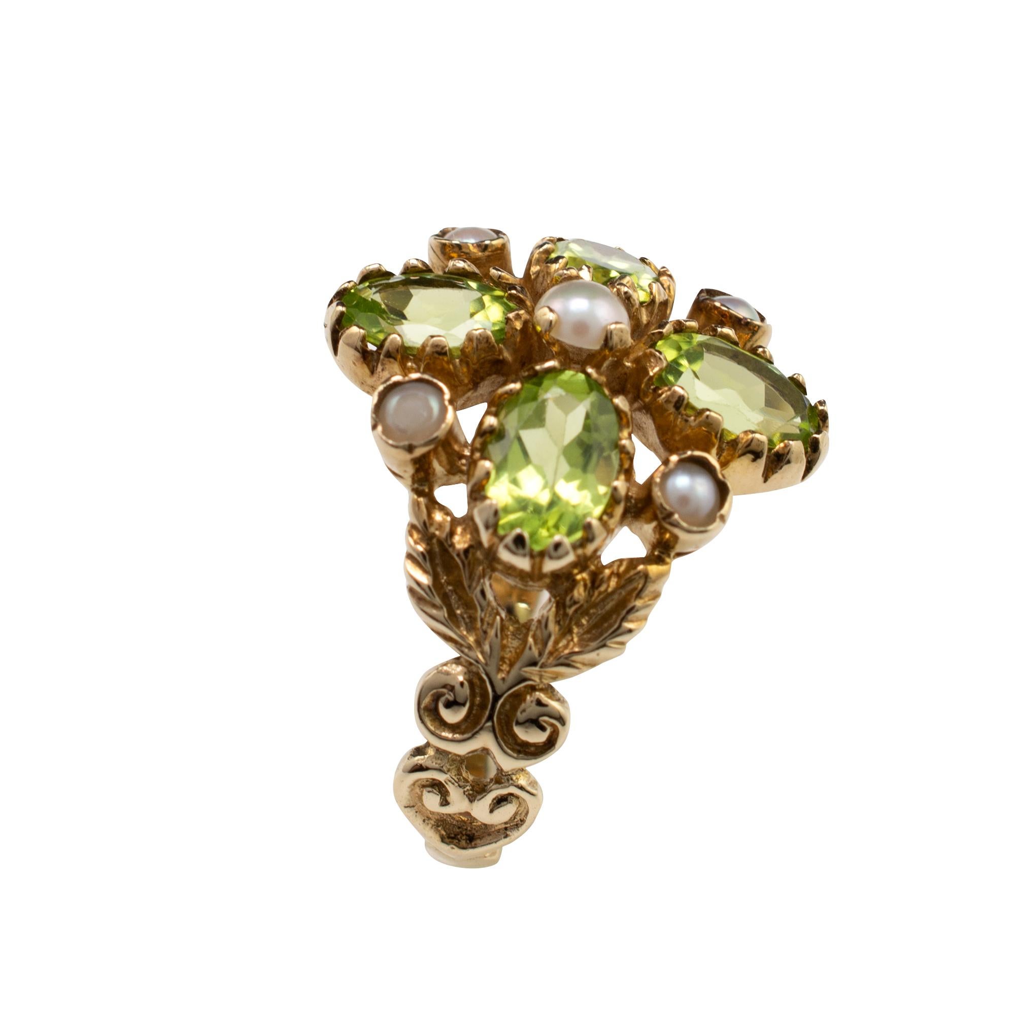This striking peridot and pearl flower cocktail ring is crafted in 9 karat gold.

The split shoulders are nicely crafted into leaves with further scroll detail. The green peridot gemstones show a beautiful translucent shade of lime green and the