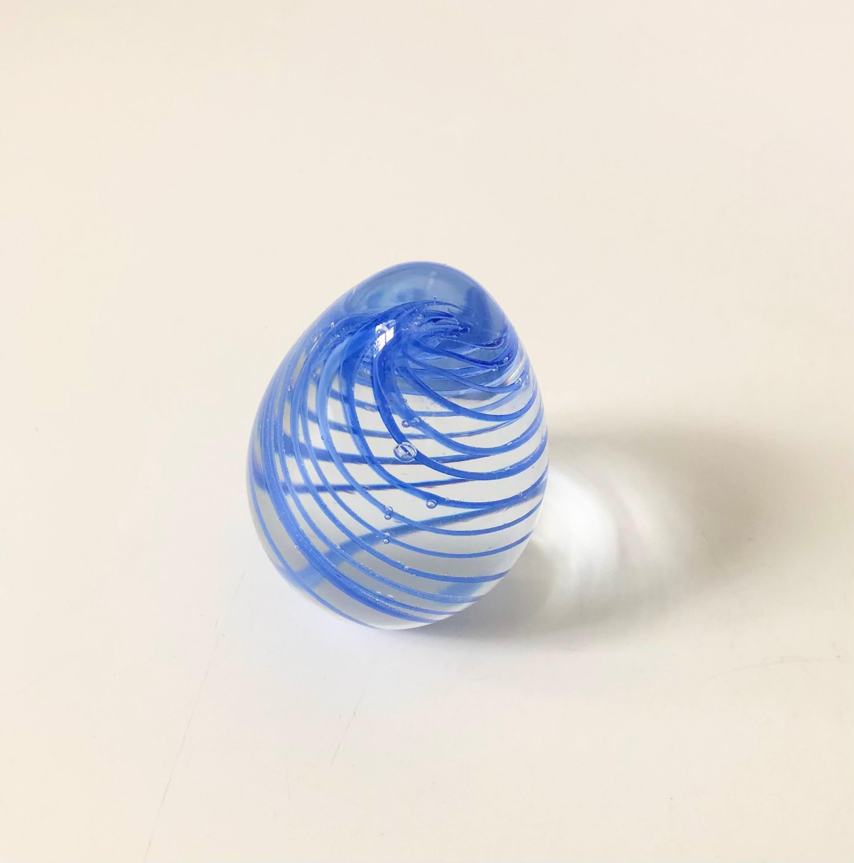 A vintage egg shaped art glass paperweight, with a beautiful swirl of periwinkle color in the center.
  
